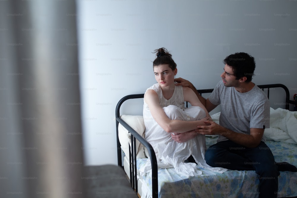 a man sitting next to a woman on a bed