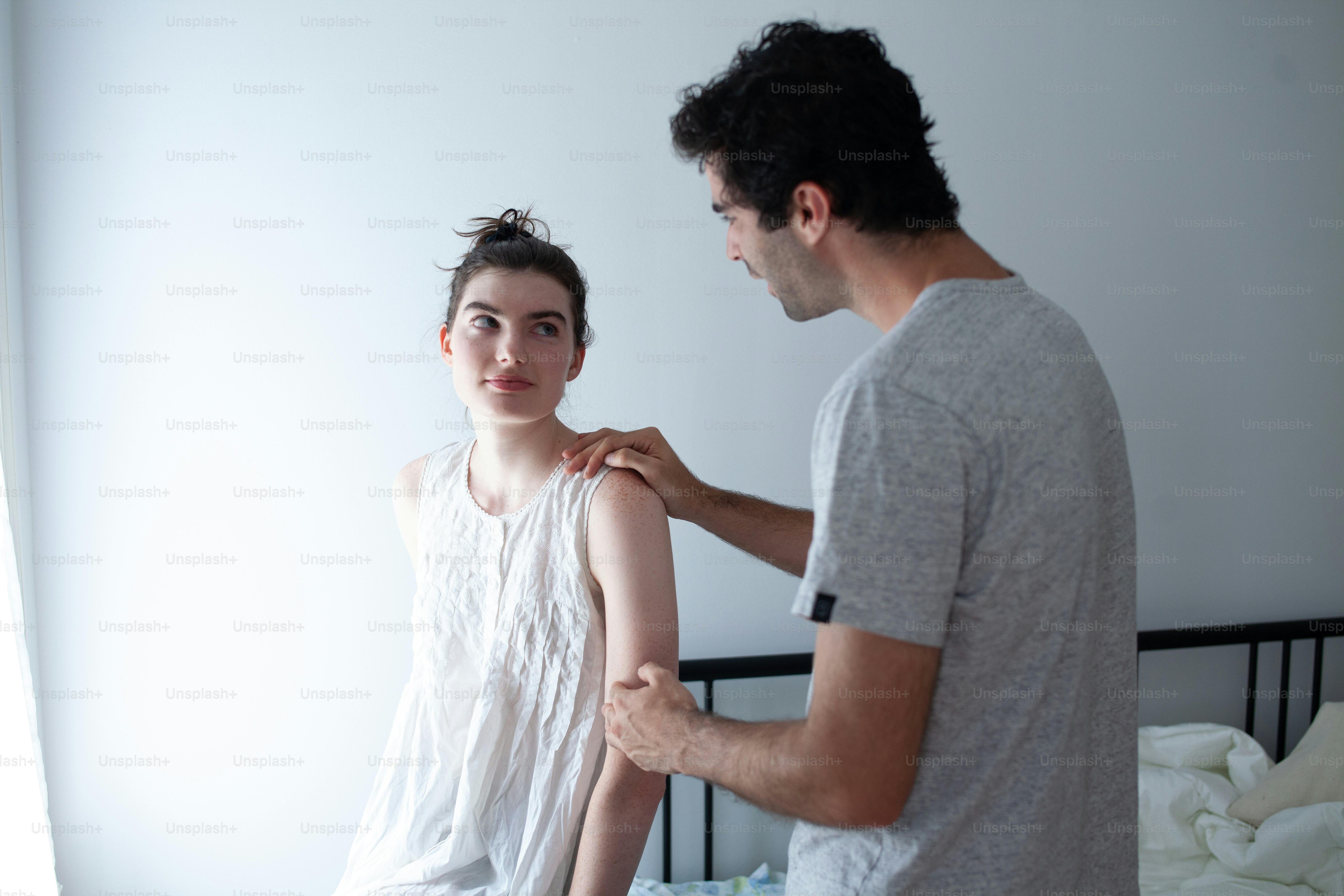 a man fixing a woman's shirt in a bedroom