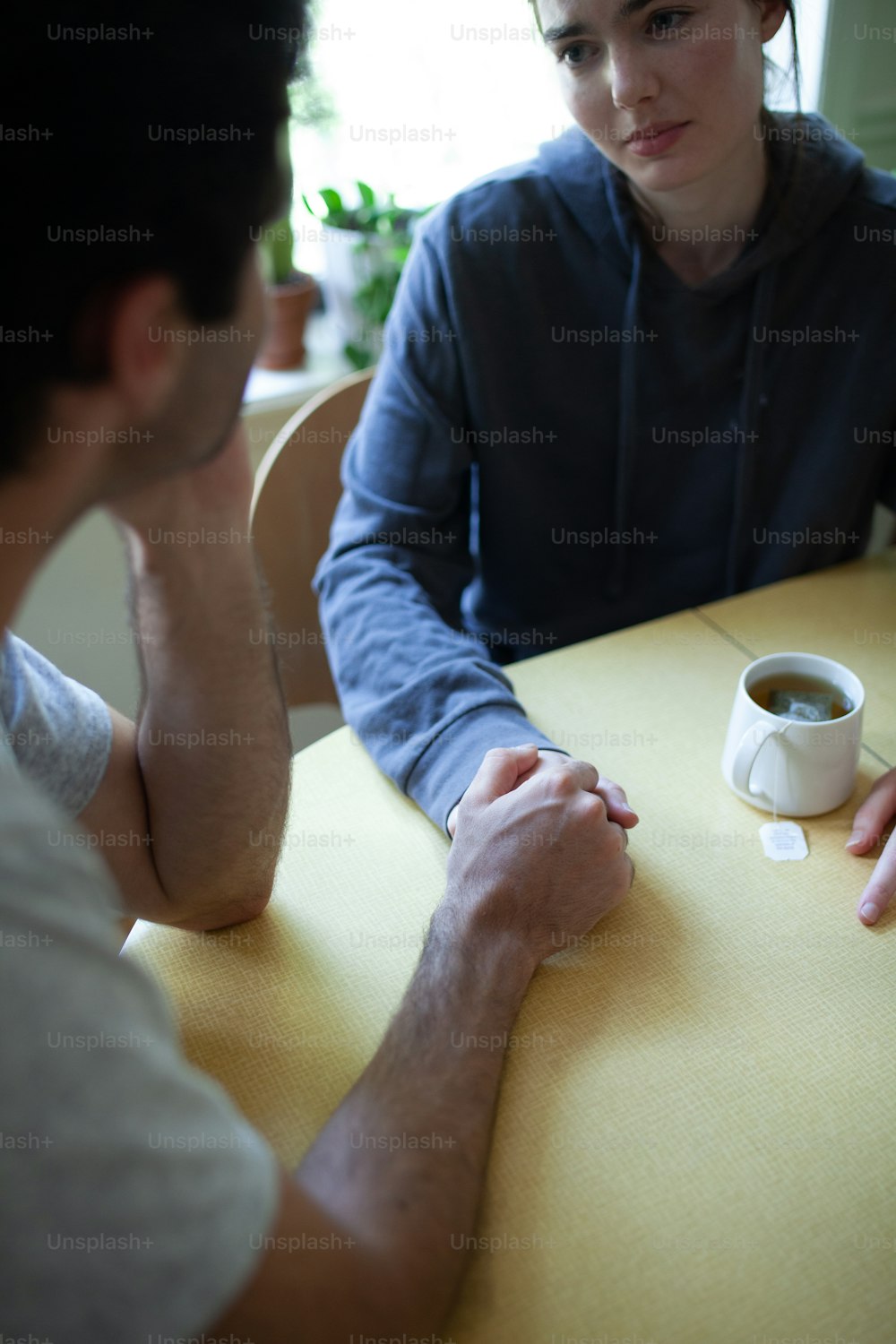 two people sitting at a table with a cup of coffee