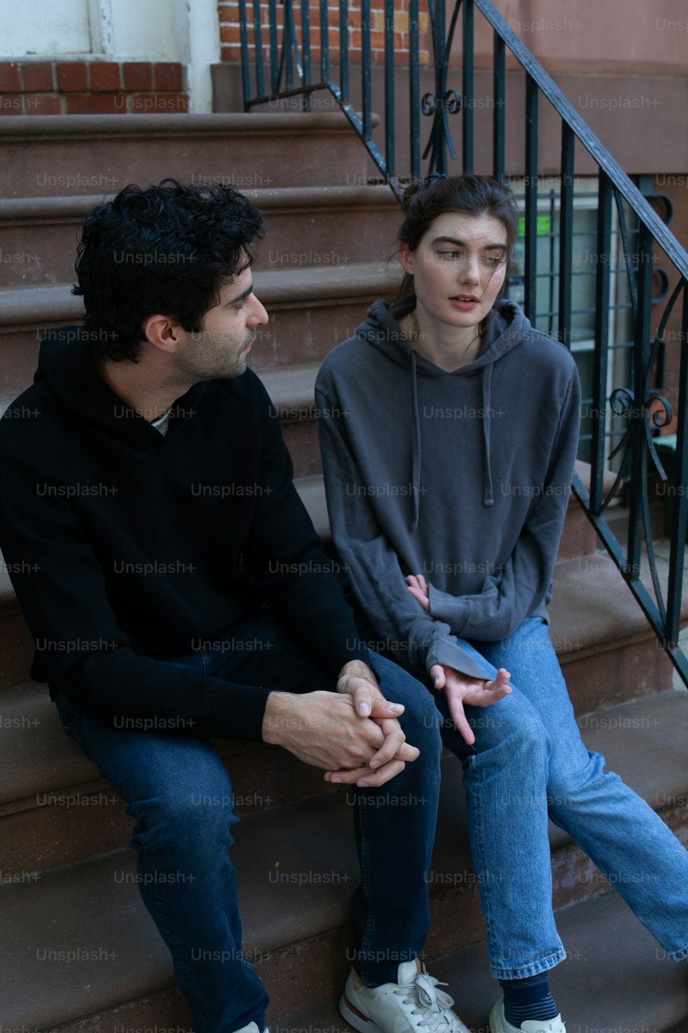 un homme et une femme assis sur les marches d’un immeuble