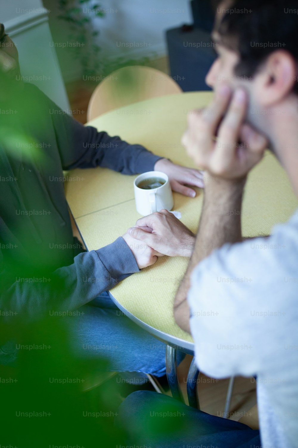 두 남자가 커피 한 잔과 함께 테이블에 앉아 있다
