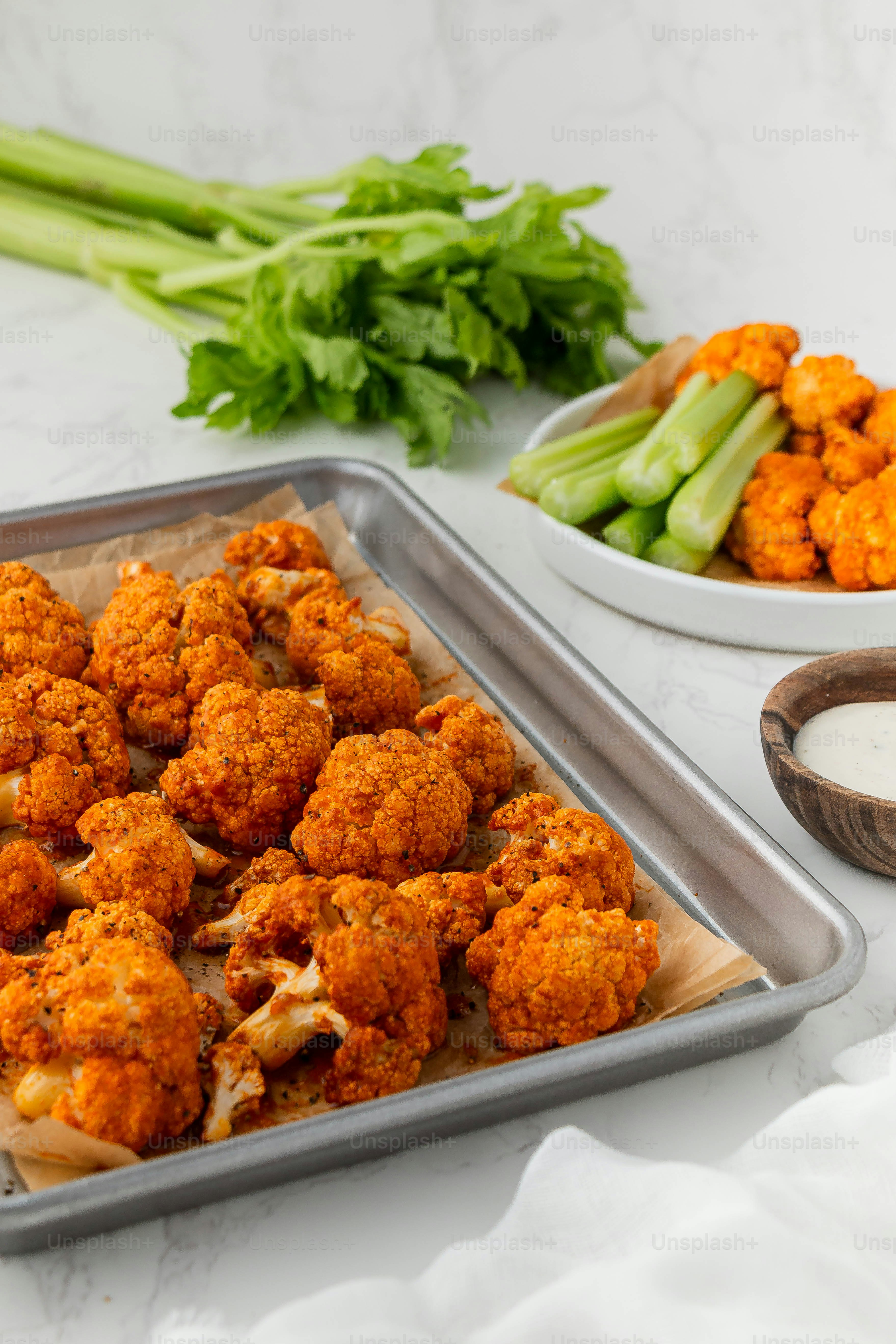 a pan filled with cauliflower next to a bowl of celery