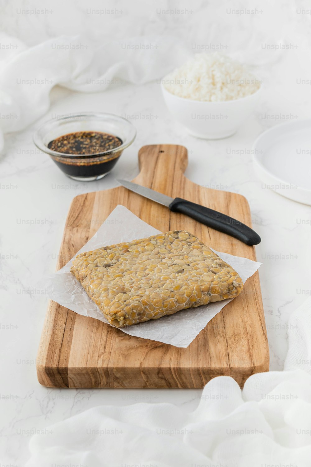 une planche à découper en bois garnie de nourriture à côté d’un bol de riz