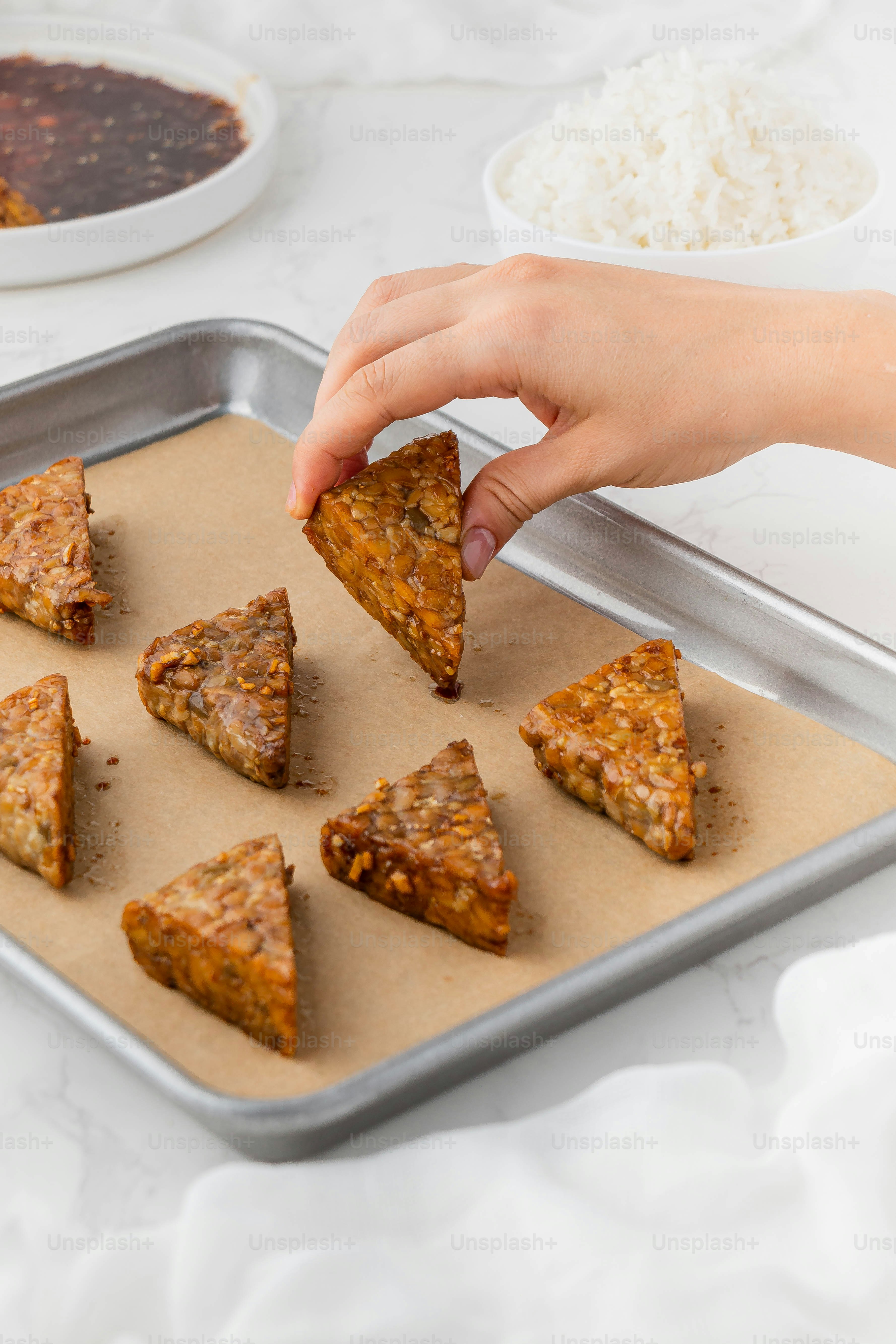 a person reaching for a piece of food on a pan