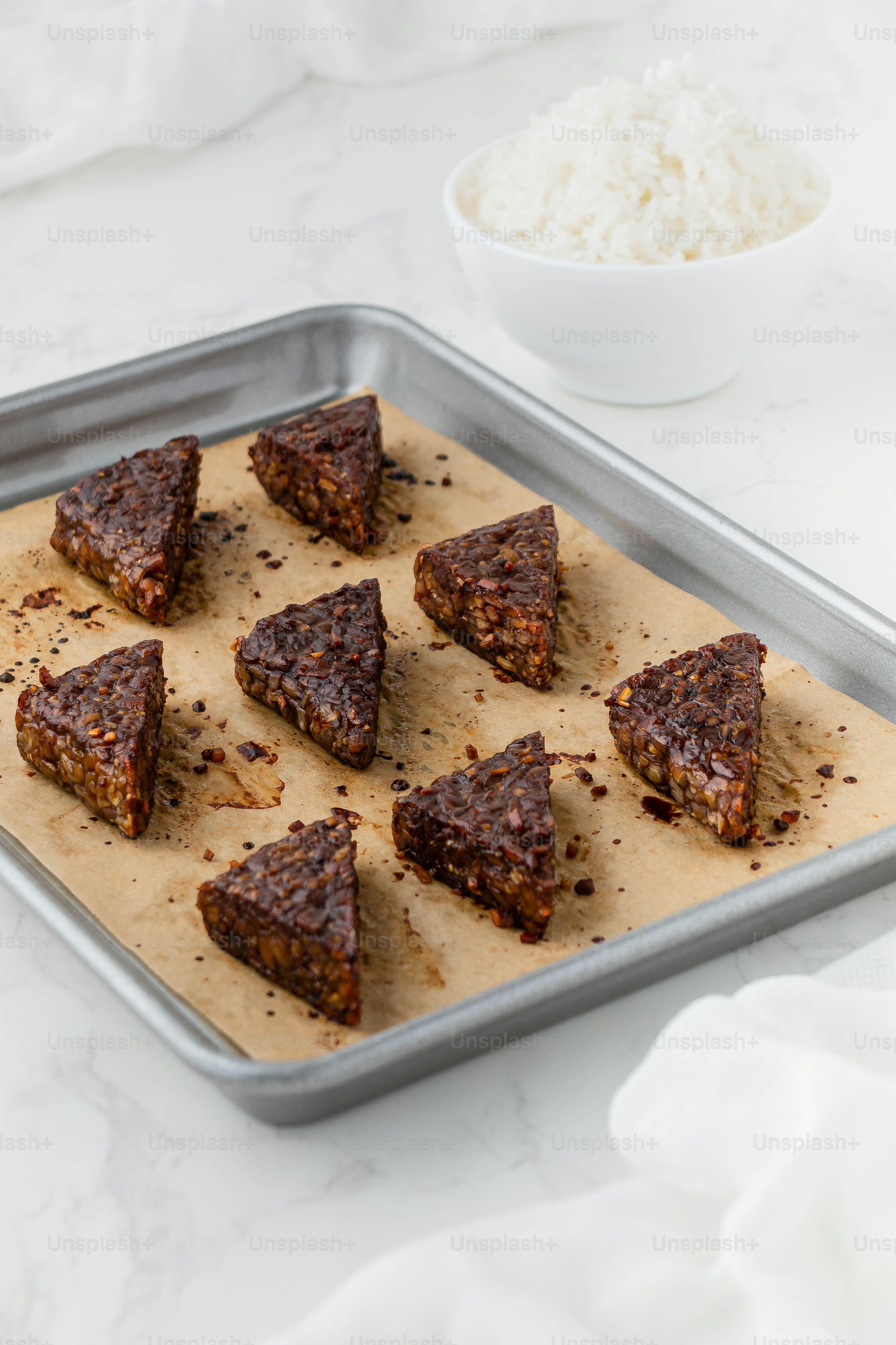a metal tray filled with brownies next to a bowl of rice