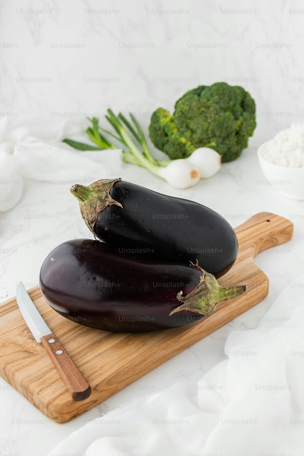 a couple of eggplant sitting on top of a wooden cutting board