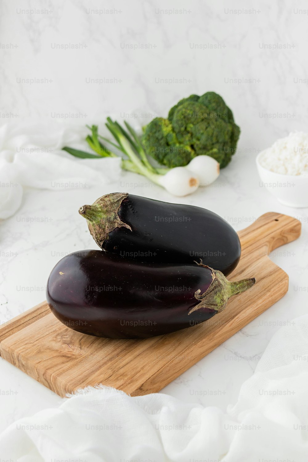 a couple of eggplant sitting on top of a wooden cutting board