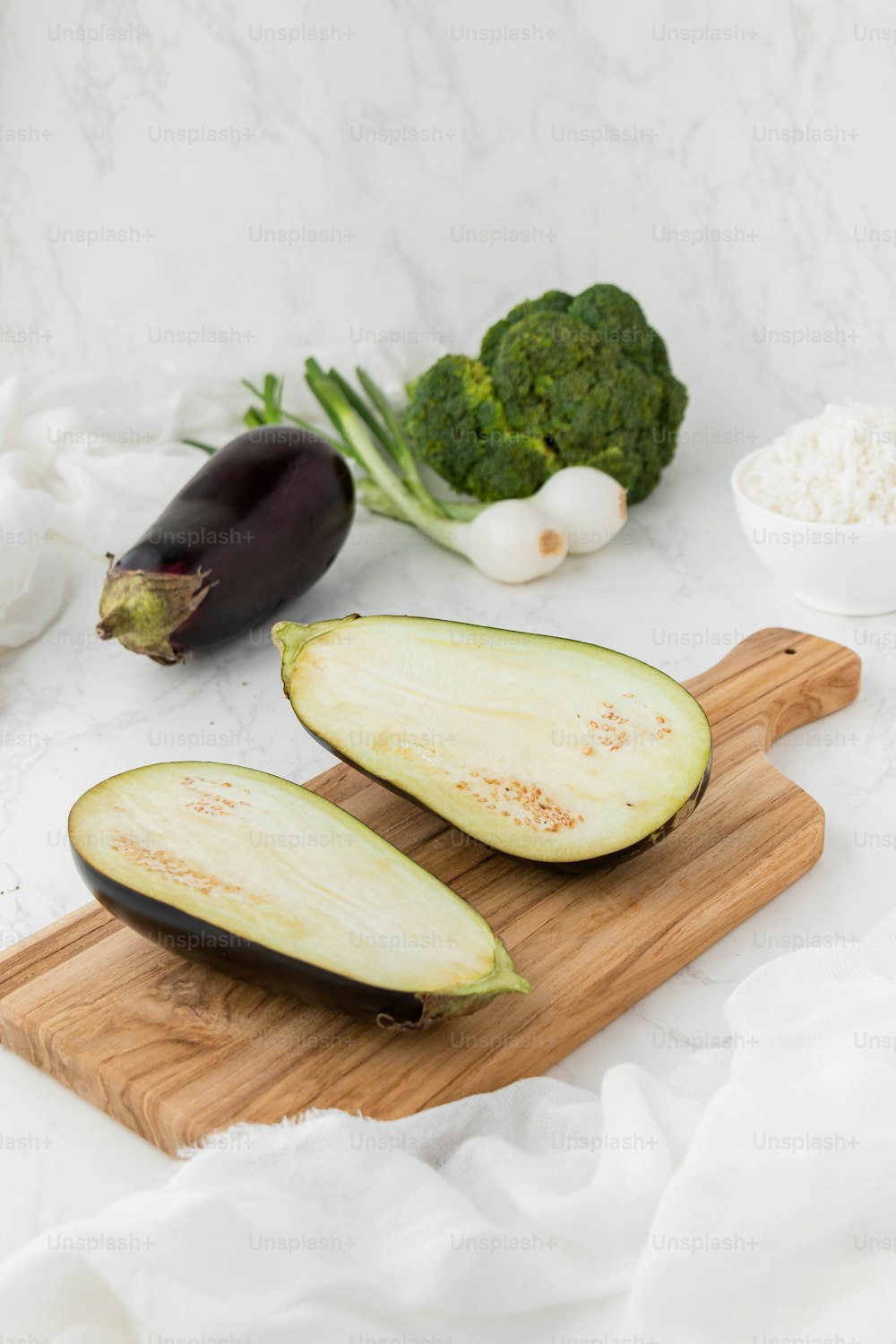 a wooden cutting board topped with eggplant and broccoli