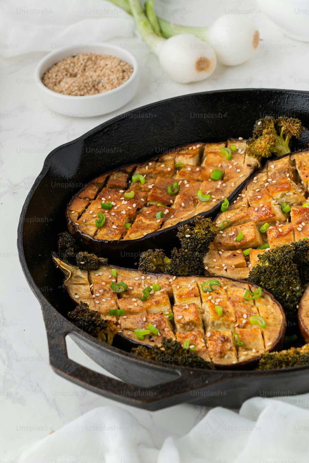 a pan filled with chicken and broccoli covered in sesame seeds