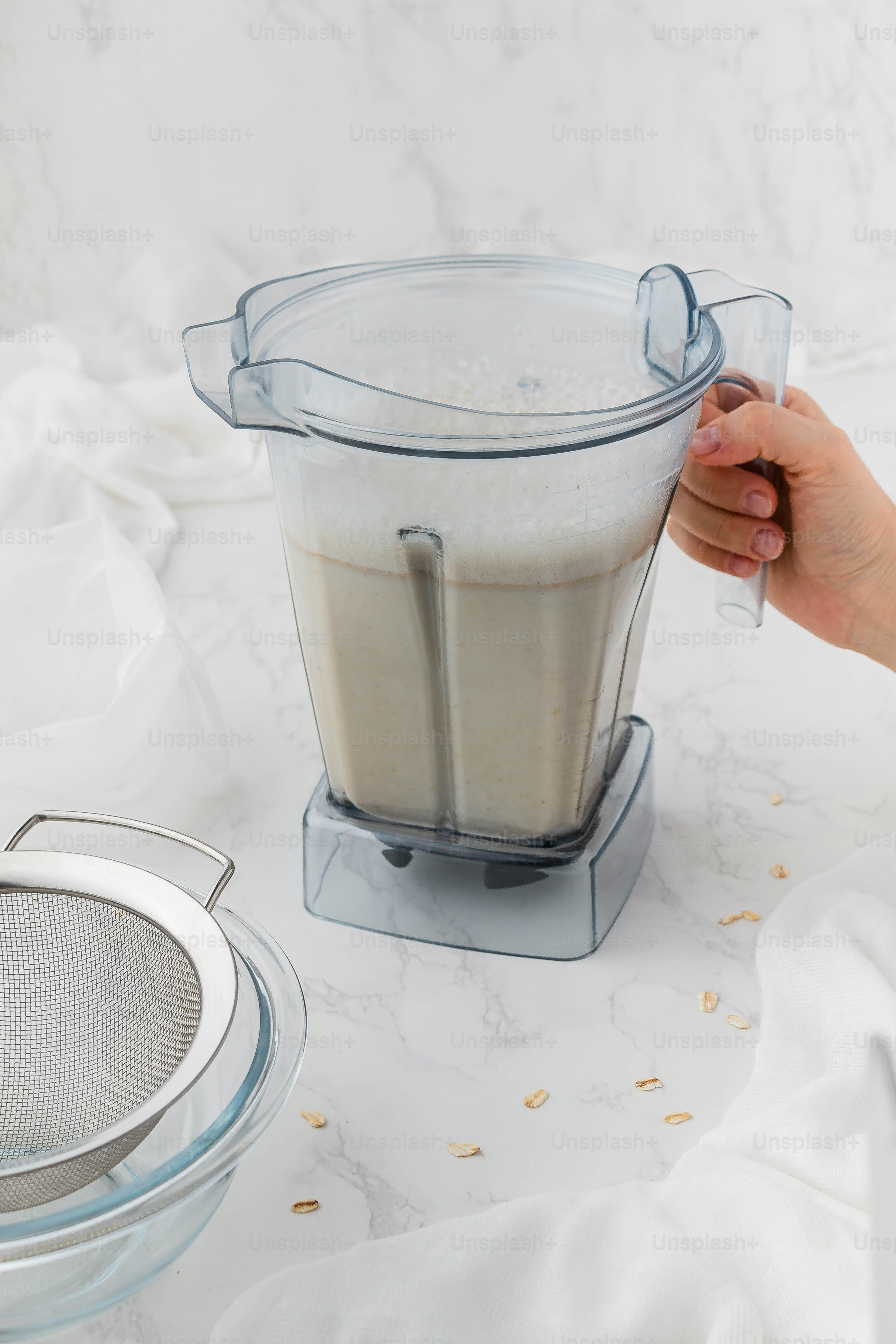 a person is holding a blender over a table