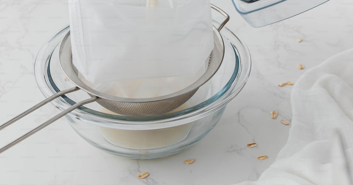 A person pouring a mixture into a blender photo – Straining Image on ...