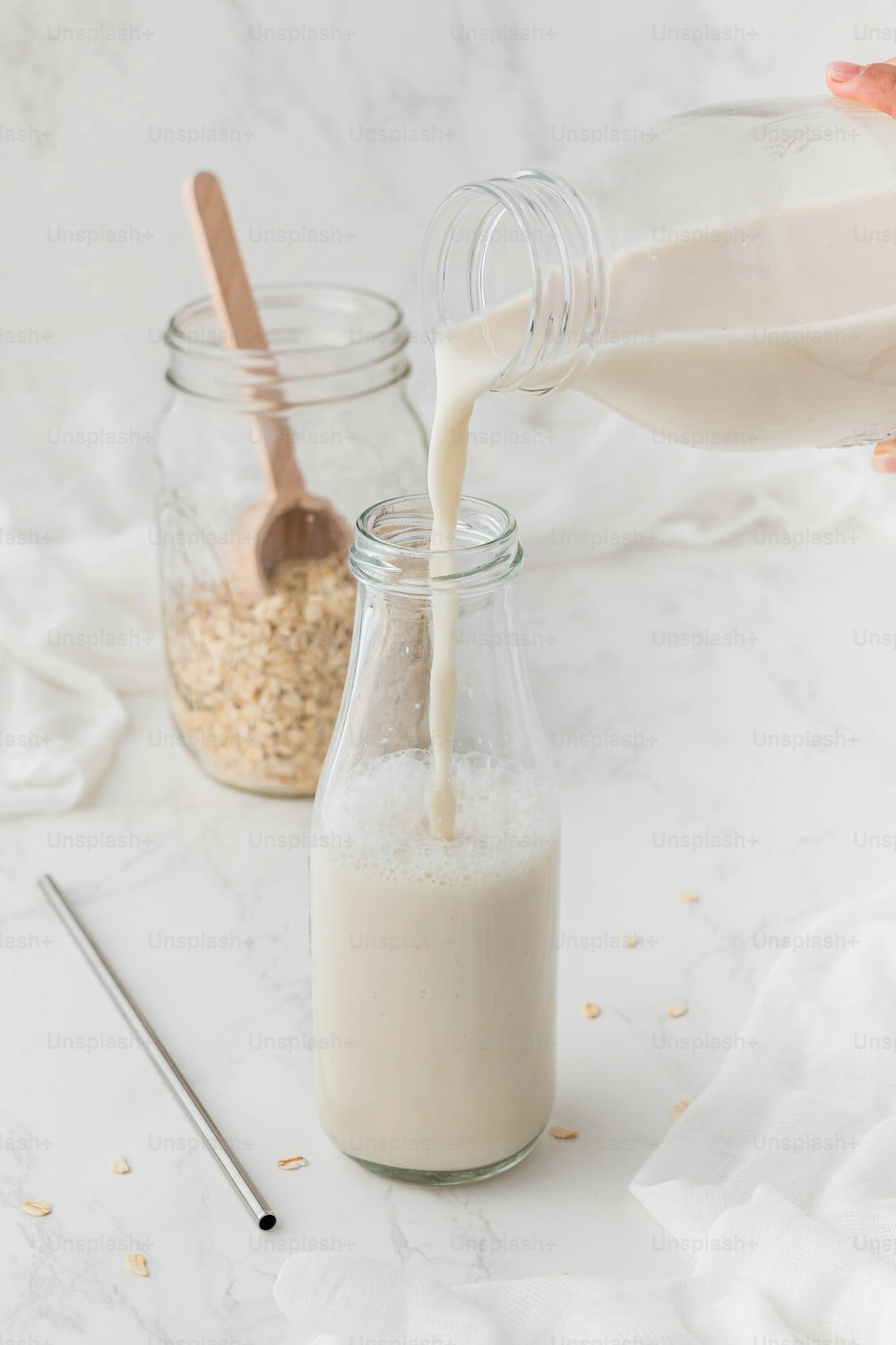 a person pouring milk into a glass jar