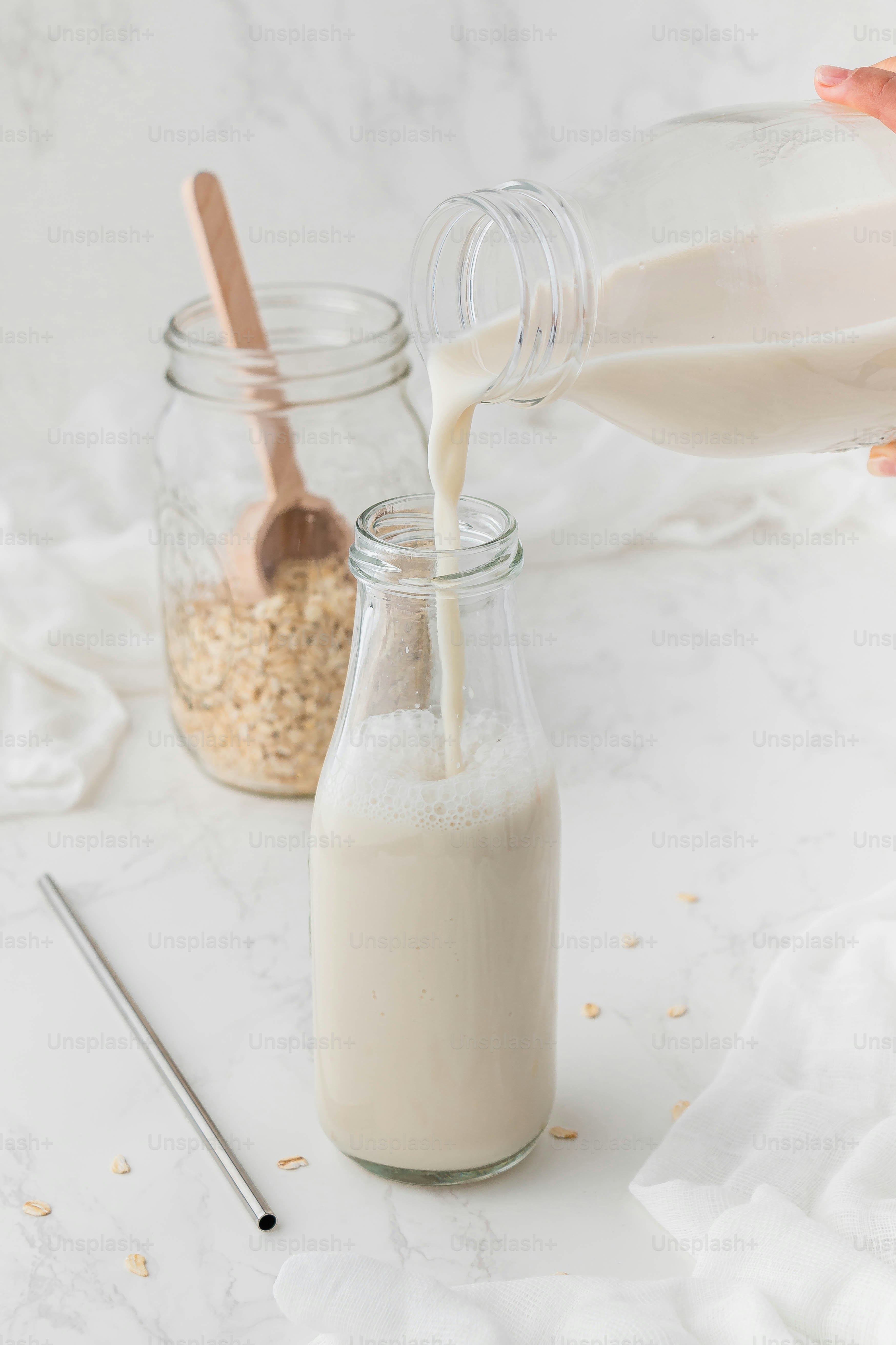 a person pouring milk into a glass jar