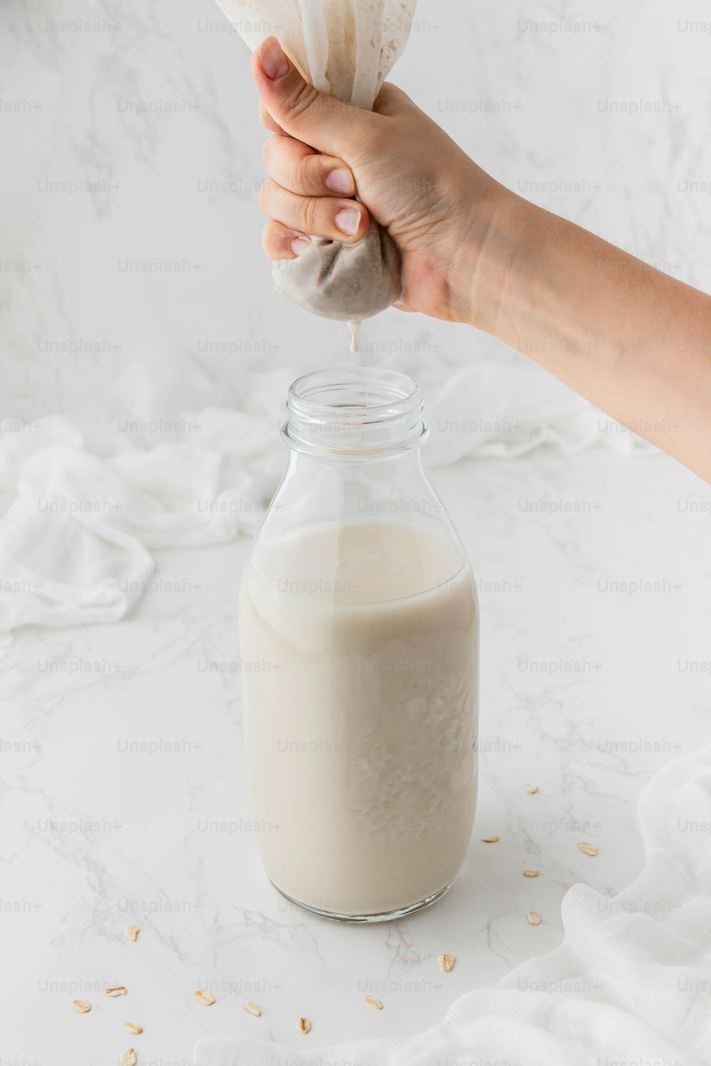 a person is pouring a glass of milk into a jar