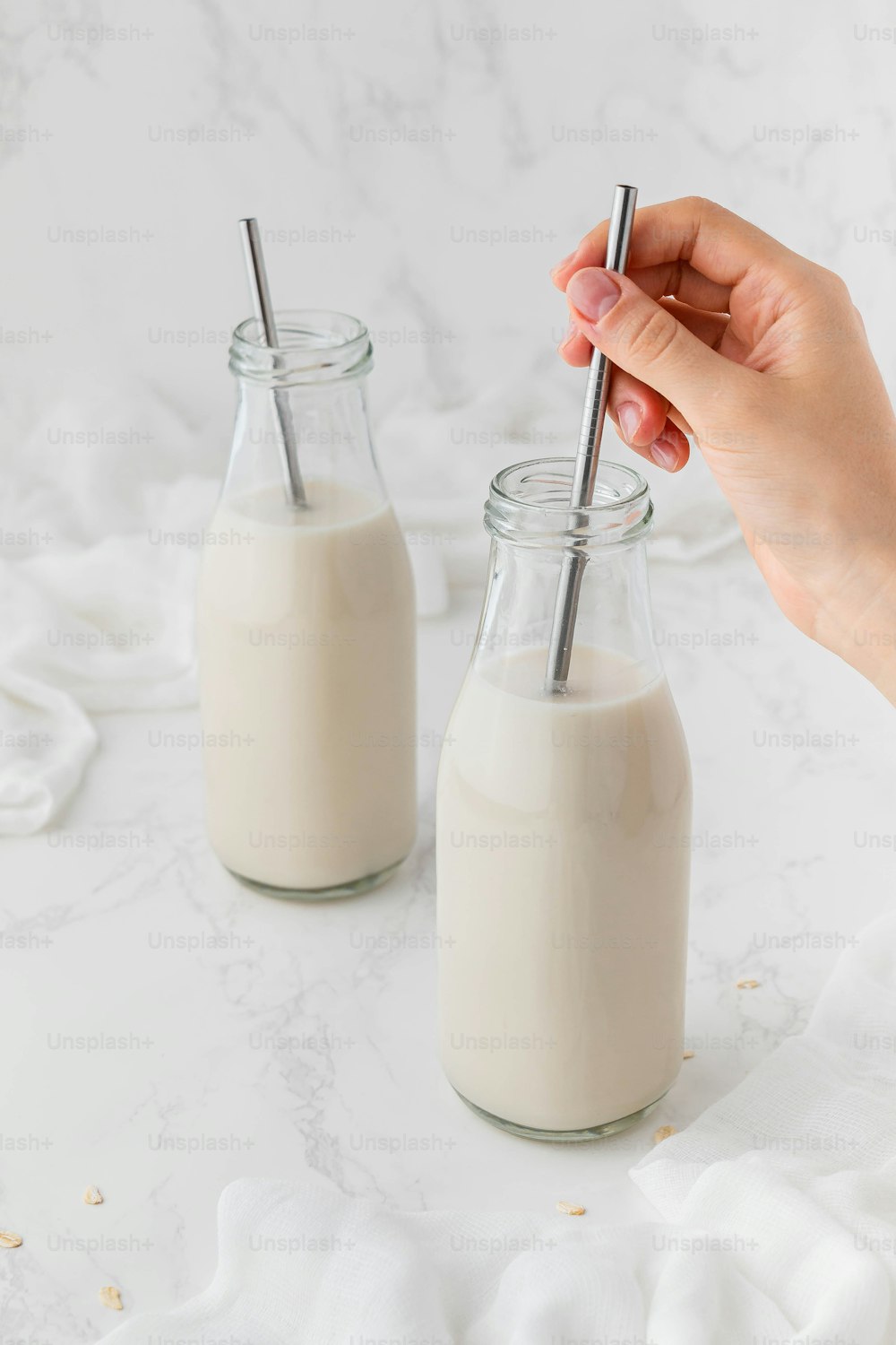 a person is holding a straw in a jar of milk
