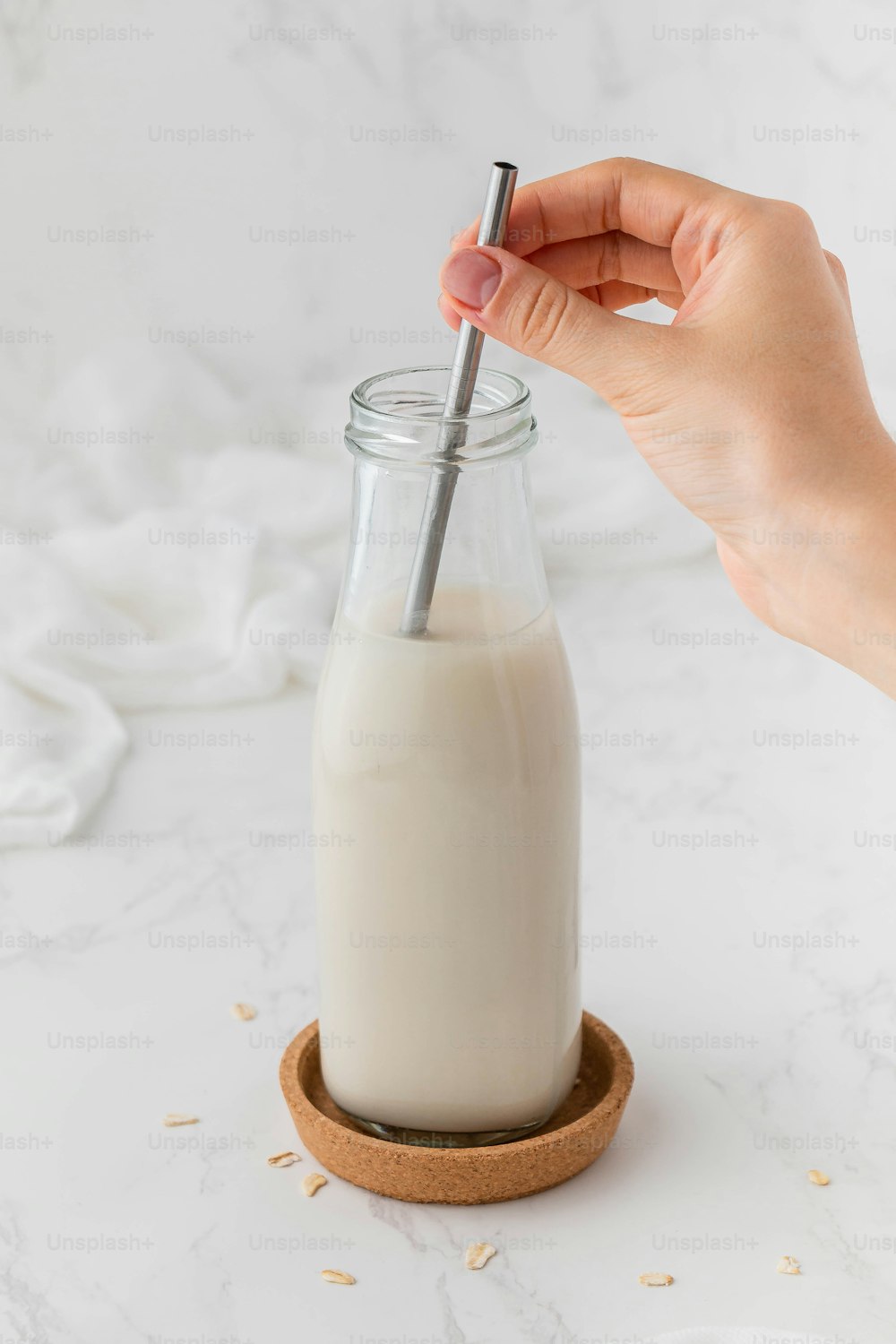 a person is holding a straw in a glass bottle