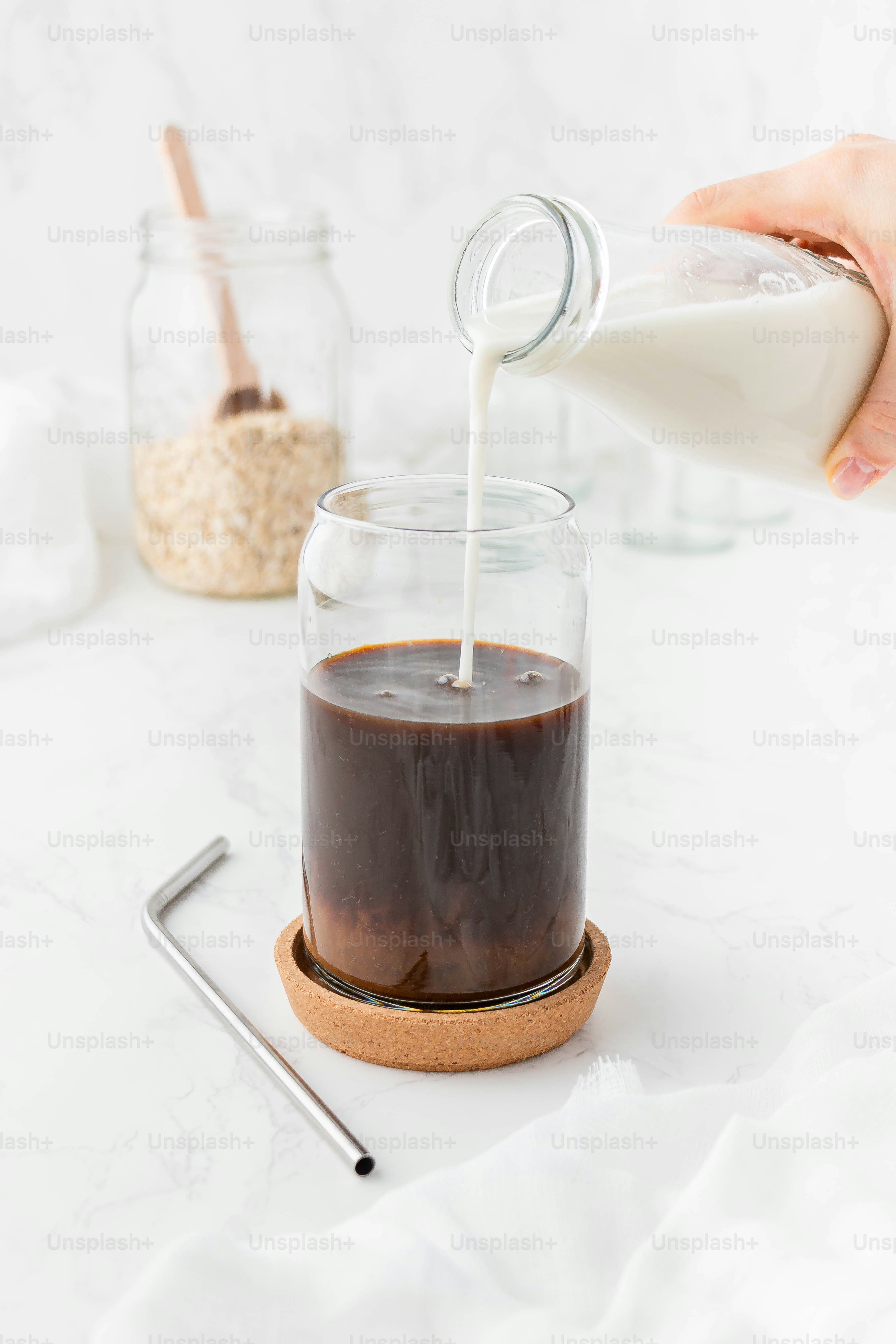 a person pouring milk into a glass jar