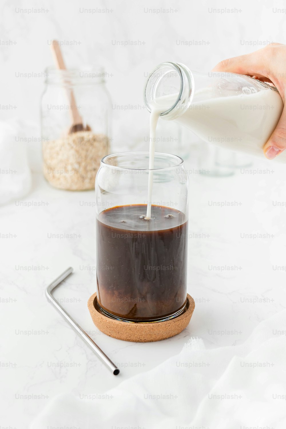 a person pouring milk into a glass jar