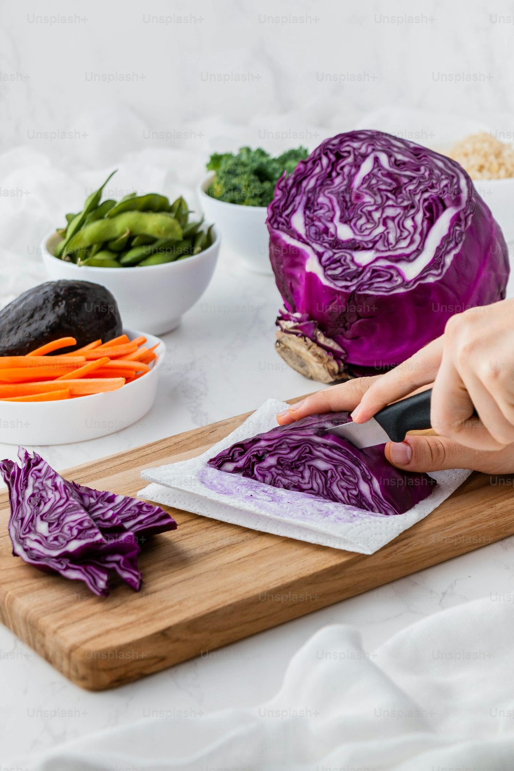 a person cutting up a cabbage on a cutting board
