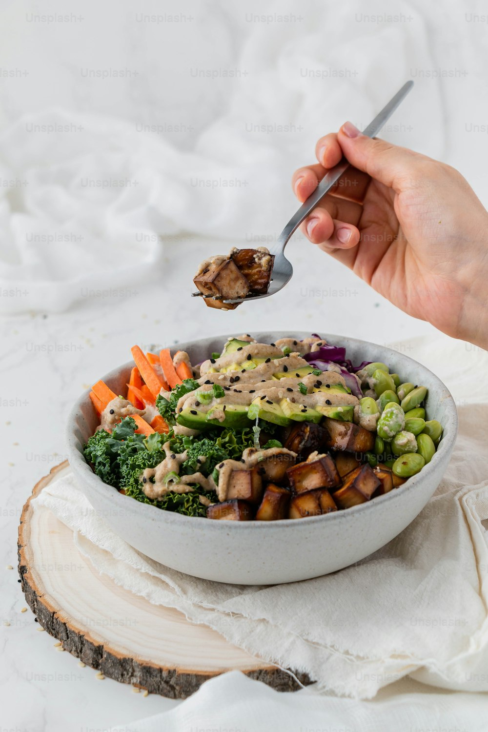 a person holding a spoon over a bowl of food