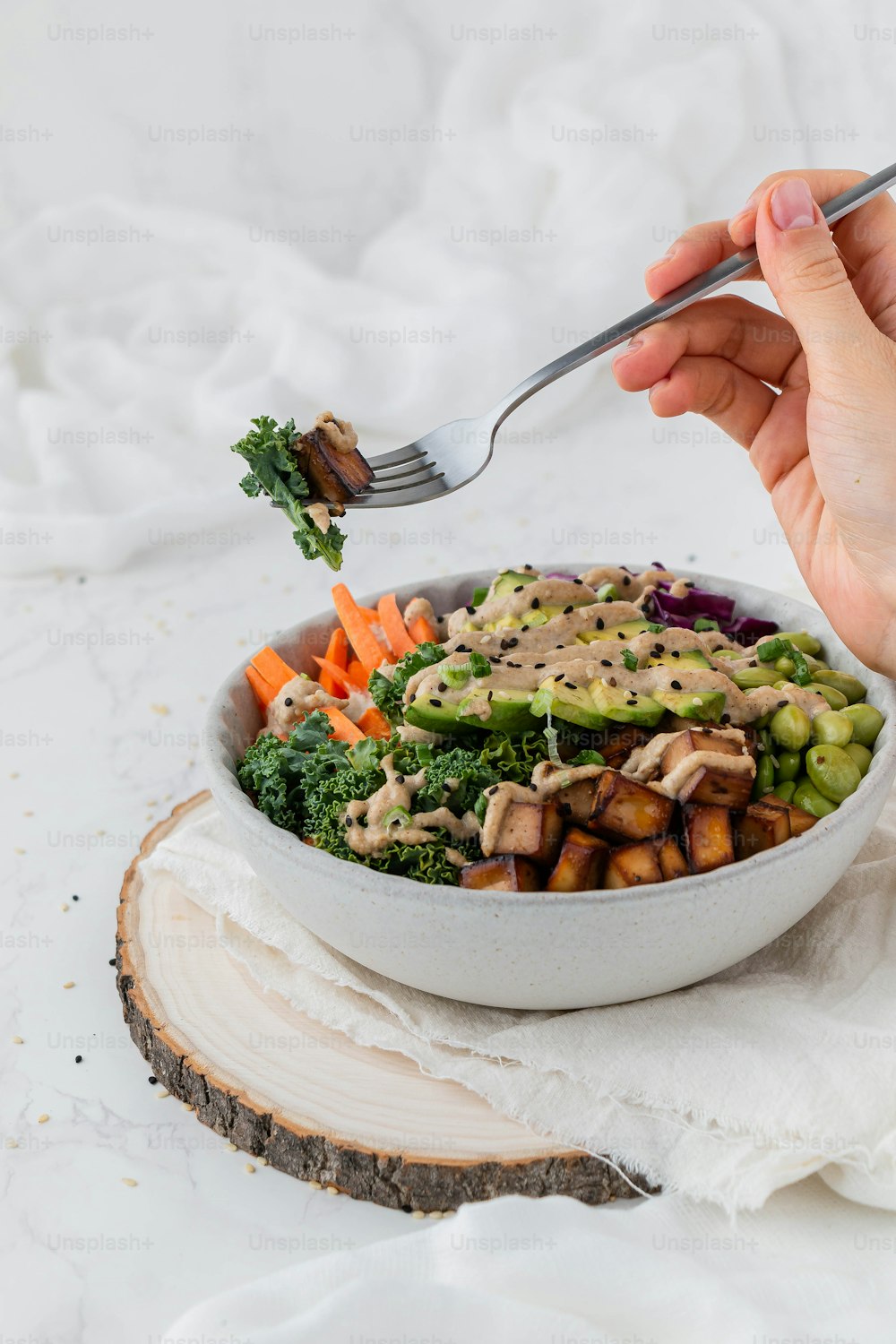 a person holding a fork over a bowl of food