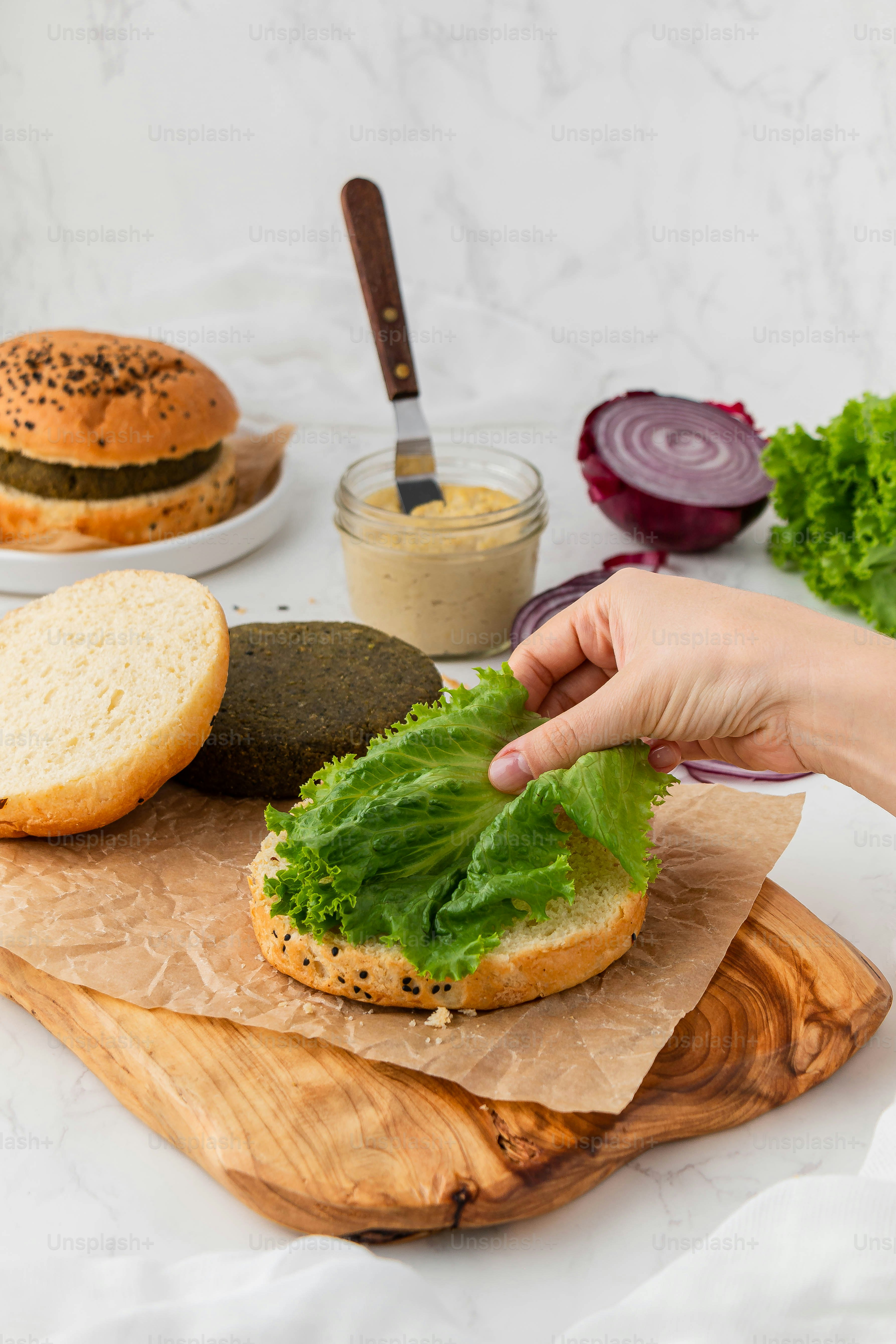 uma pessoa está colocando alface em um bagel