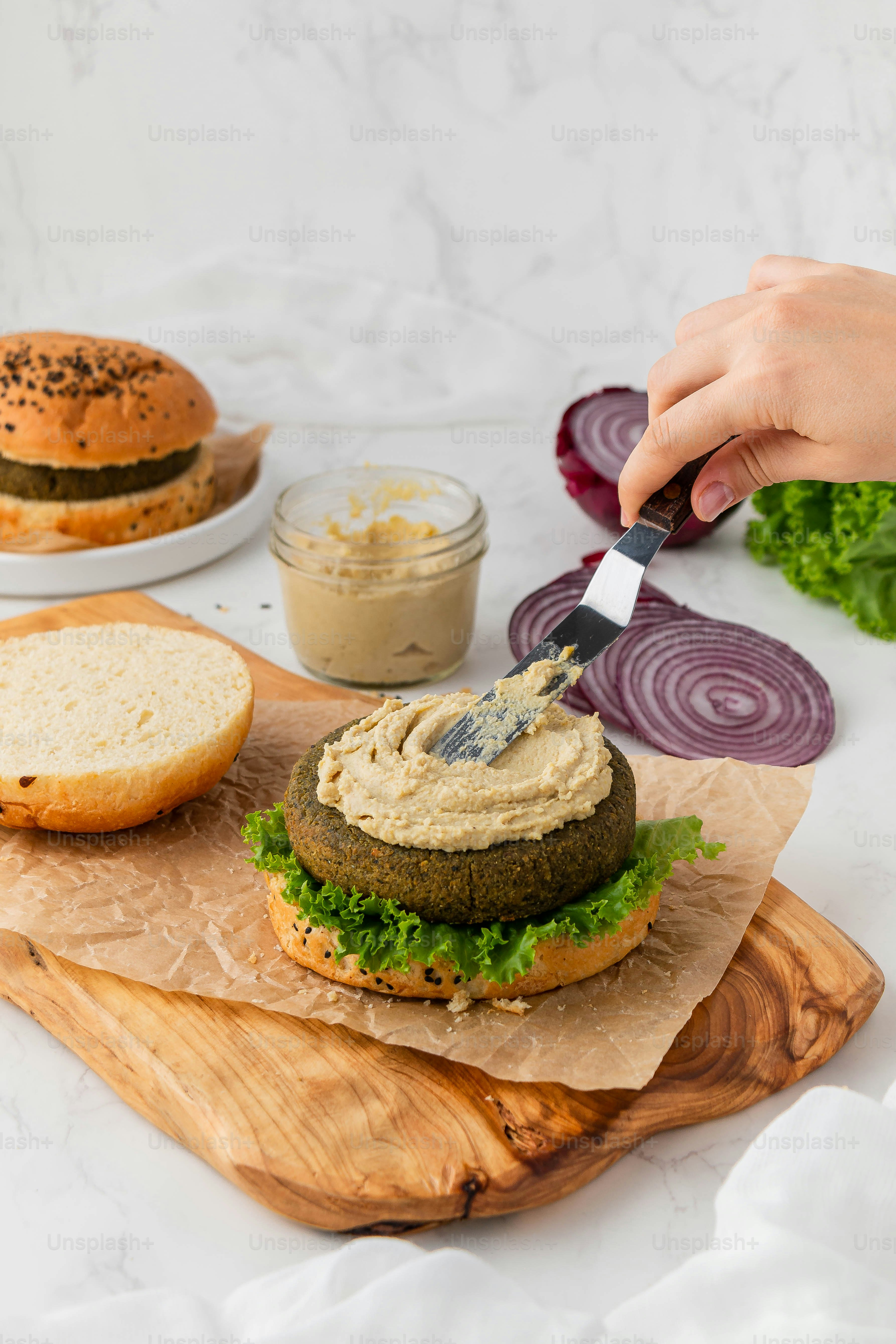 a person cutting up a large hamburger on a cutting board