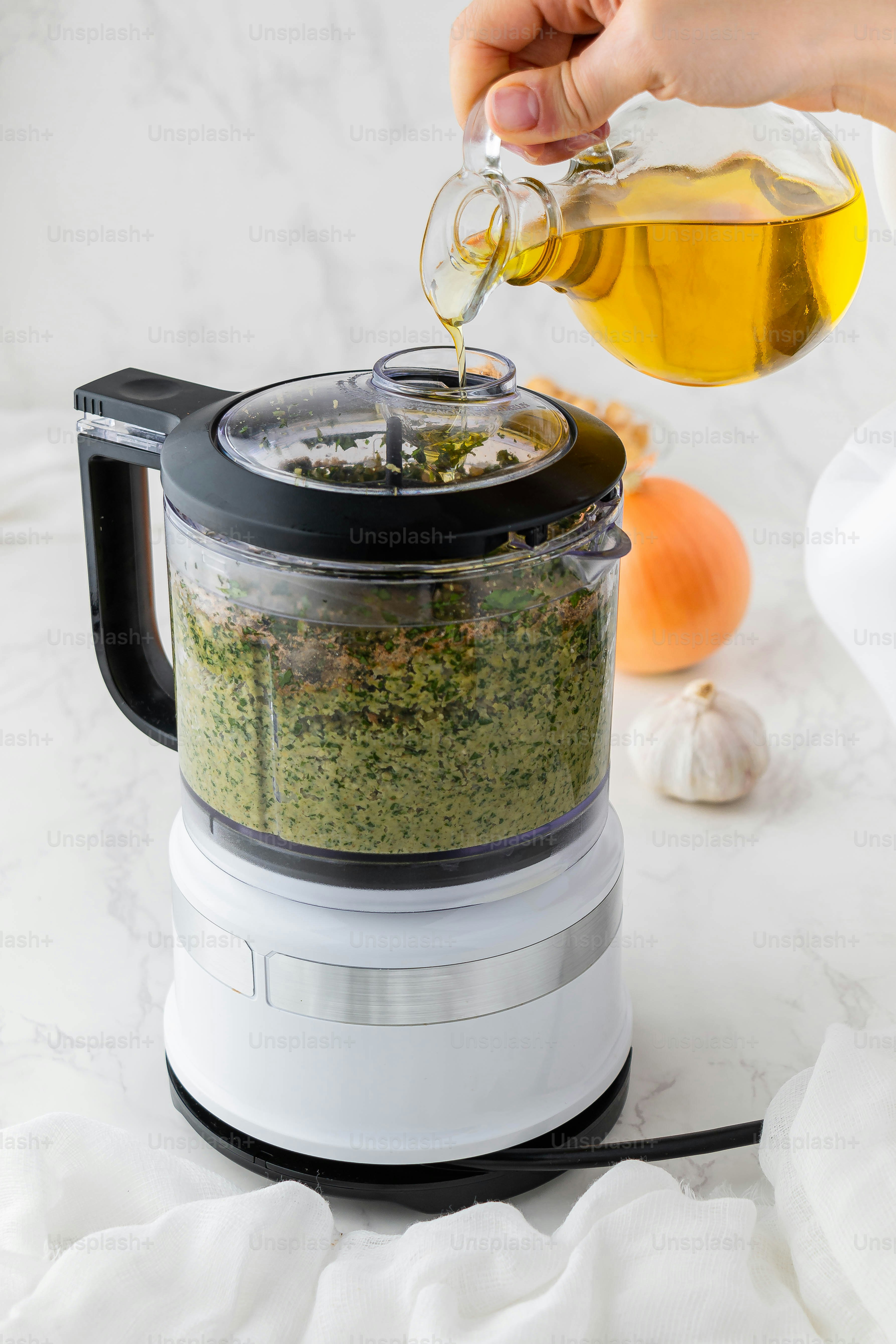 a person pouring olives into a food processor