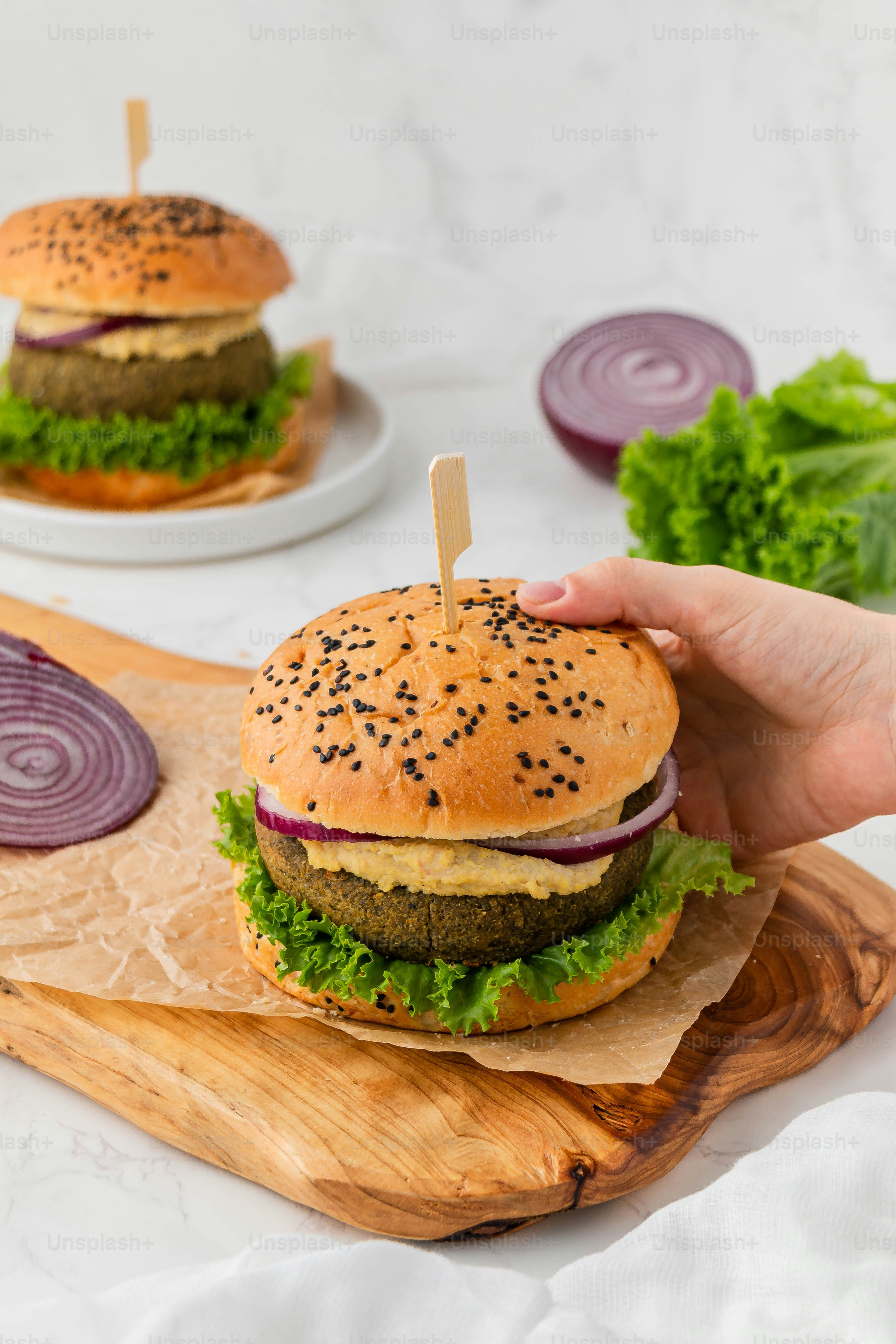 a hand holding a hamburger on a cutting board