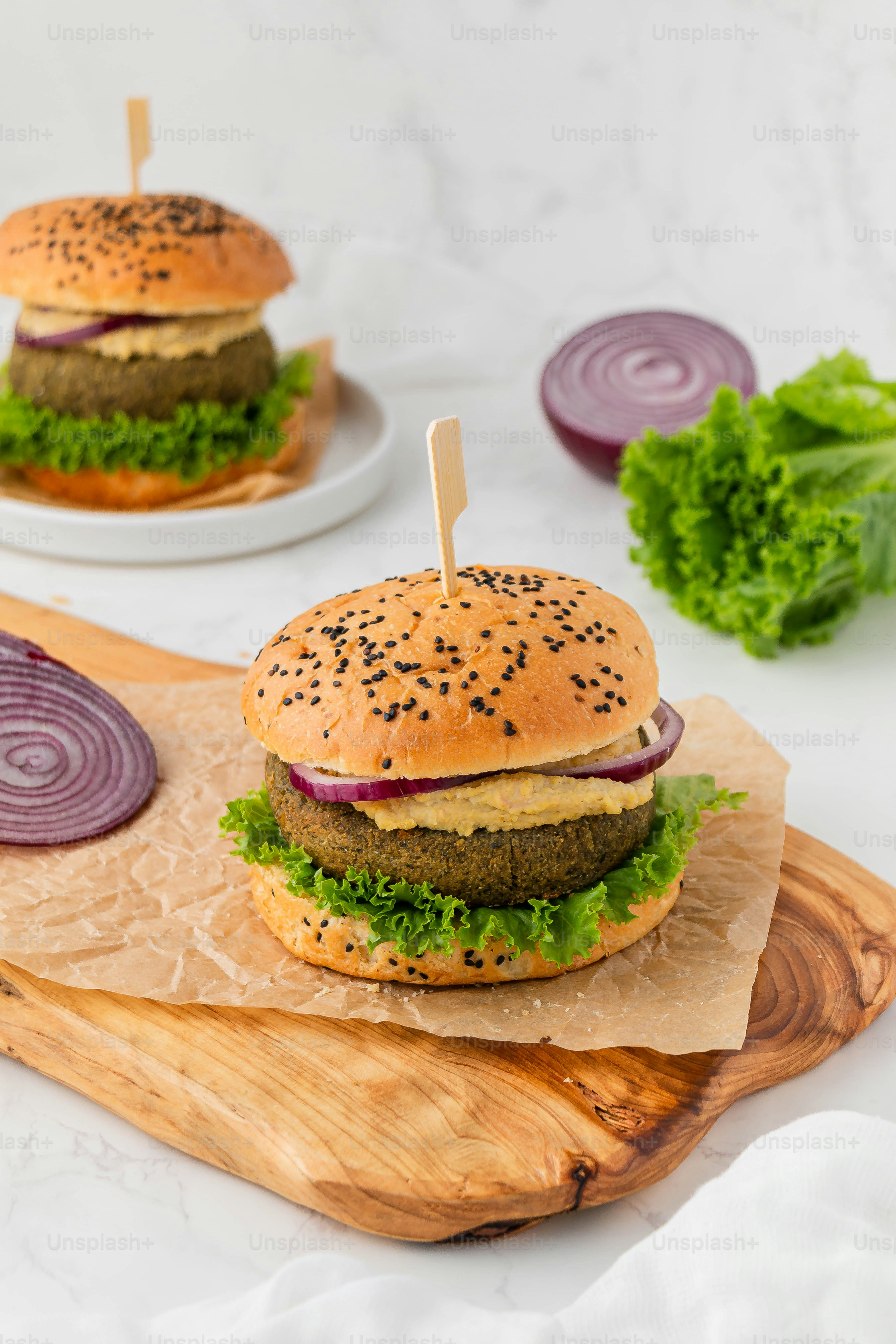 a hamburger with lettuce and onion on a cutting board