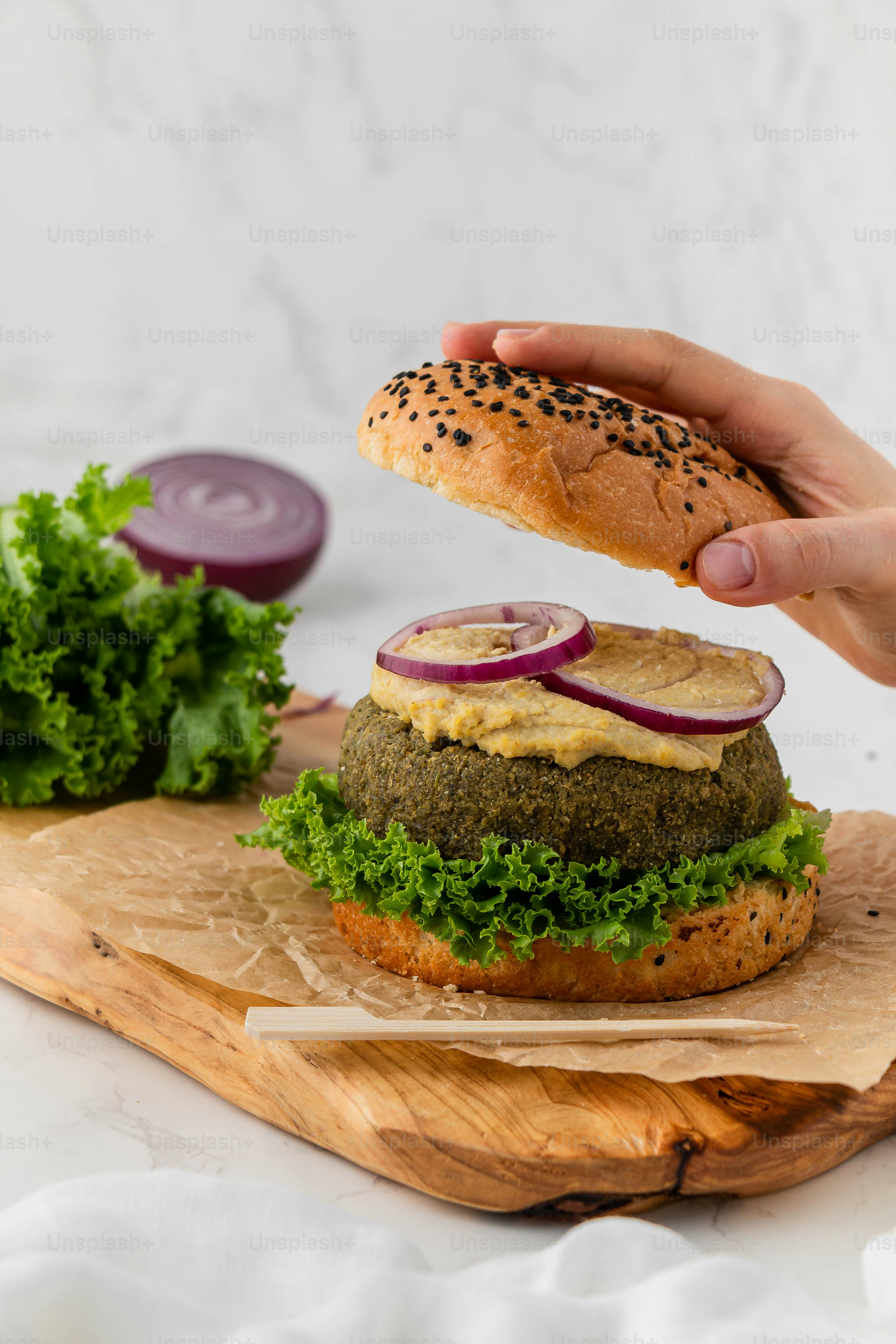 a hand reaching for a sandwich on a cutting board