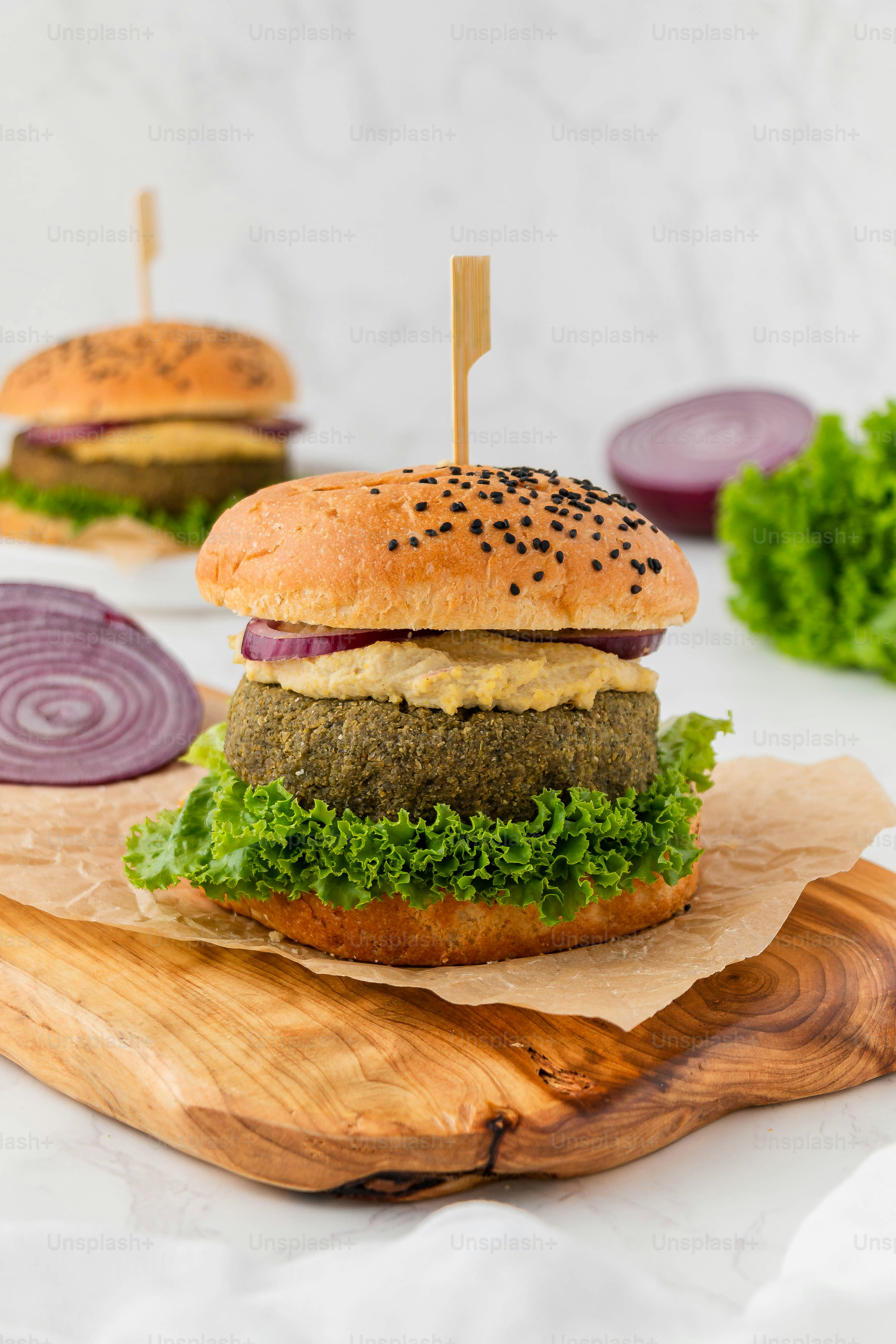 a hamburger with lettuce and onion on a cutting board