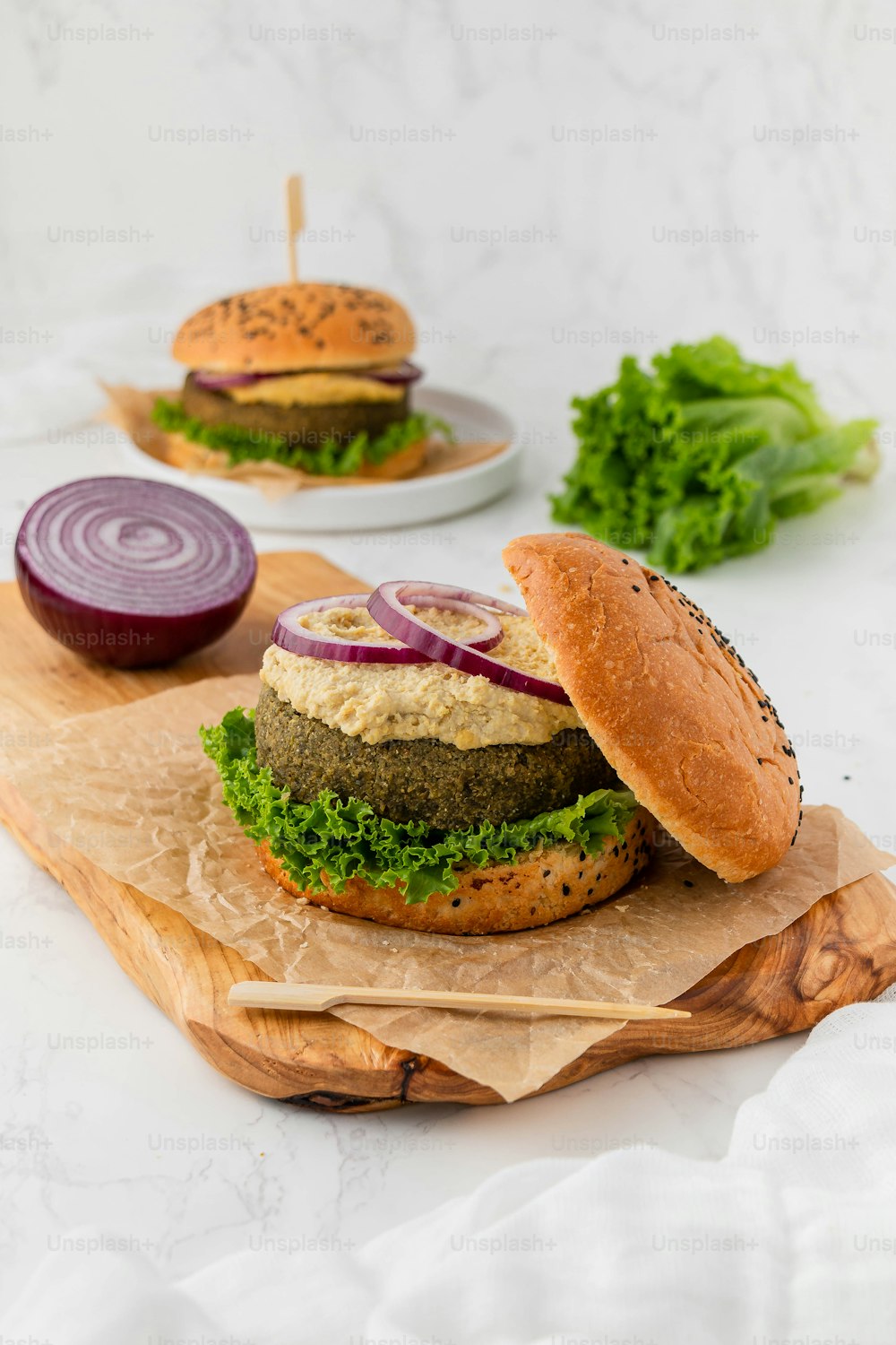 a hamburger with lettuce and onion on a cutting board