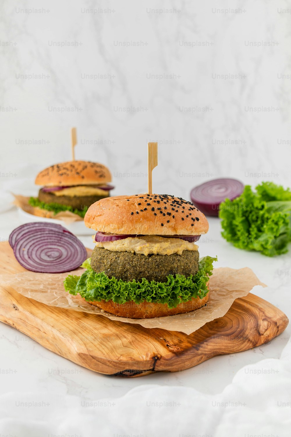a hamburger with lettuce and onion on a cutting board