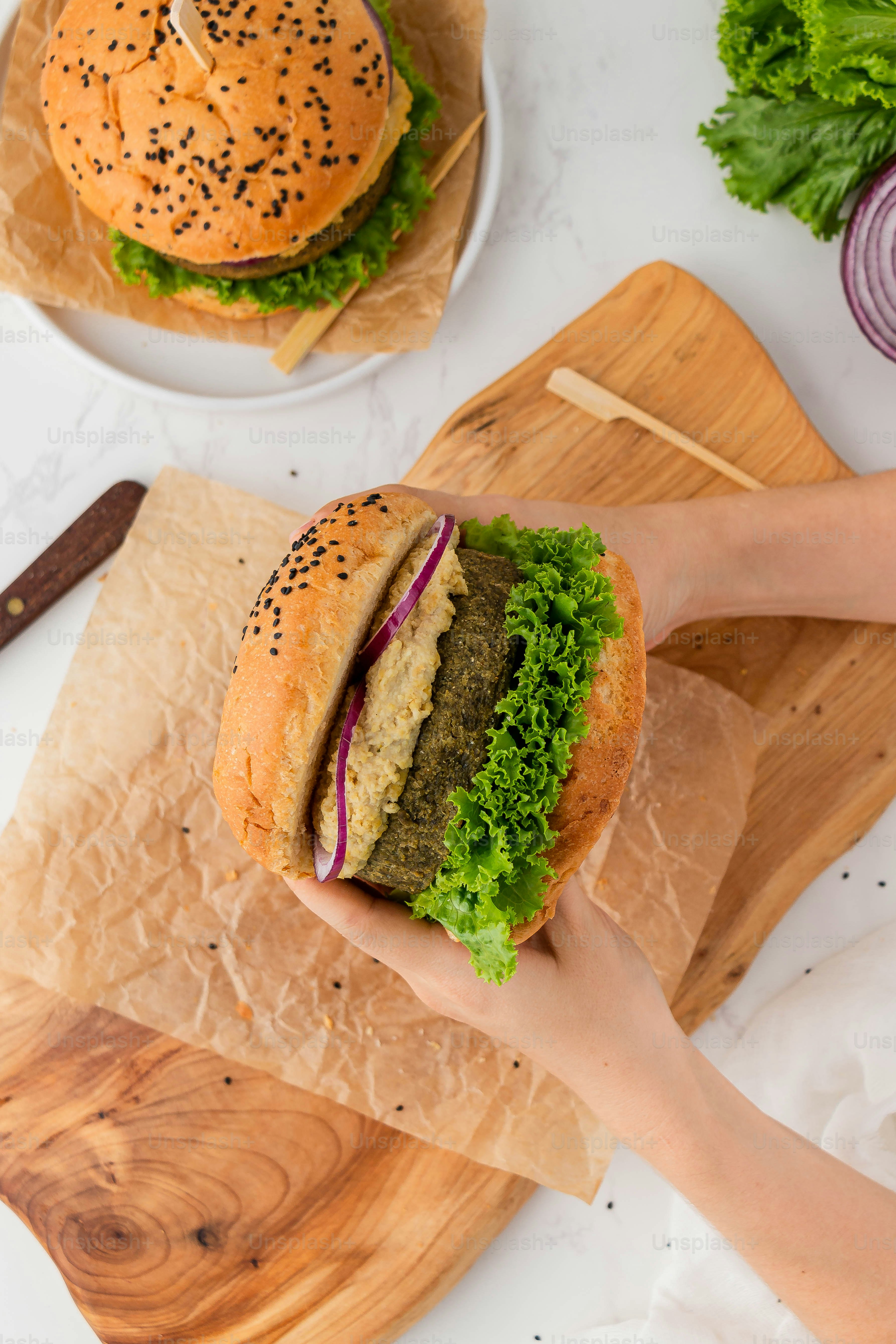 a person holding a large sandwich on a cutting board