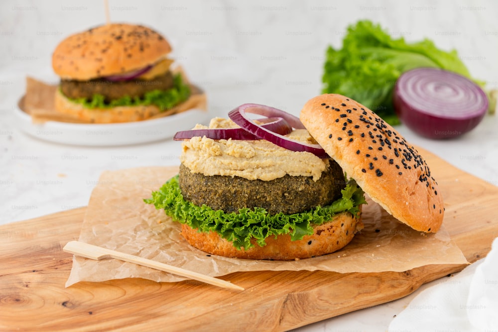 a hamburger with lettuce and onion on a cutting board