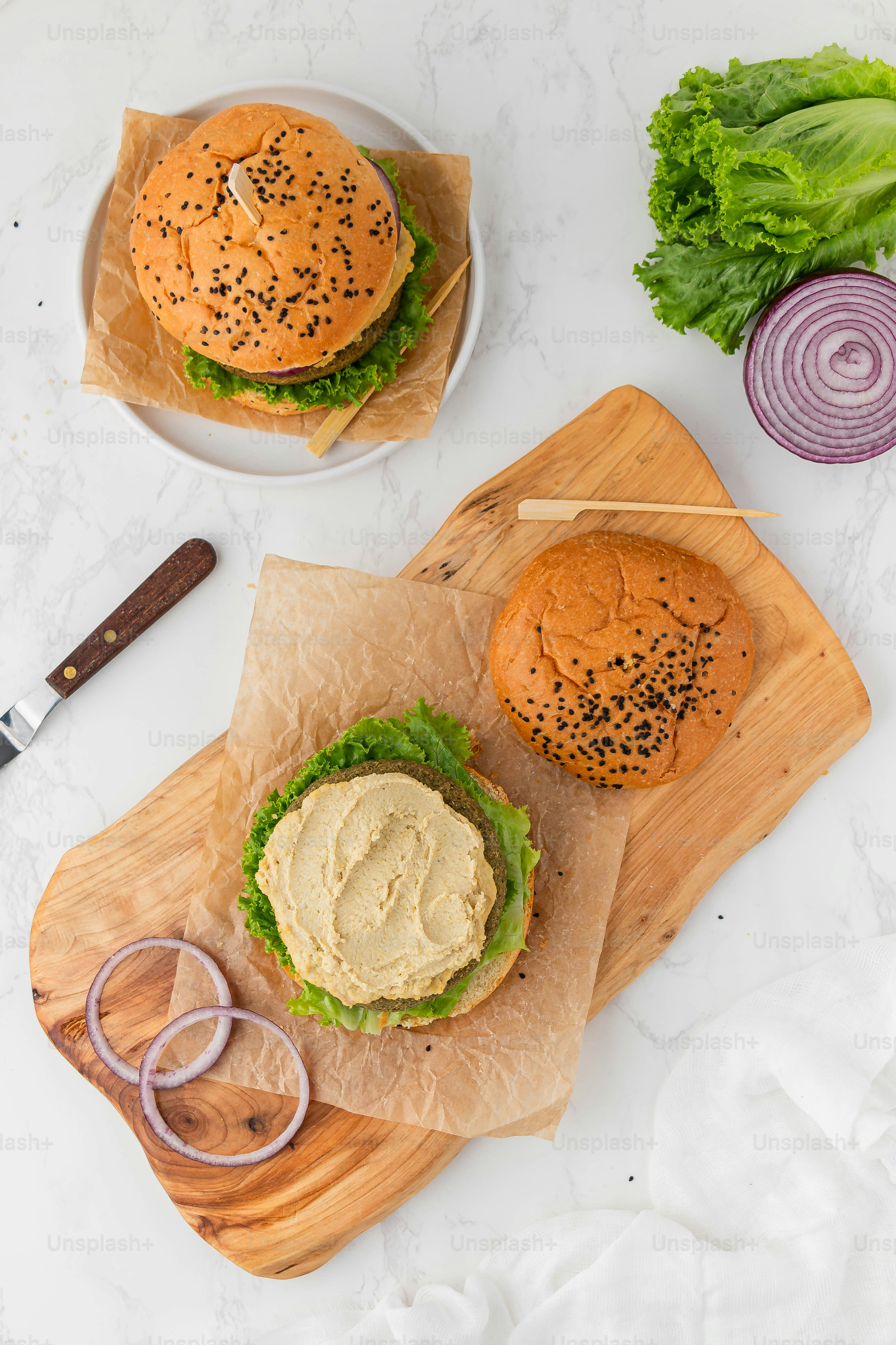 two burgers sitting on top of a wooden cutting board