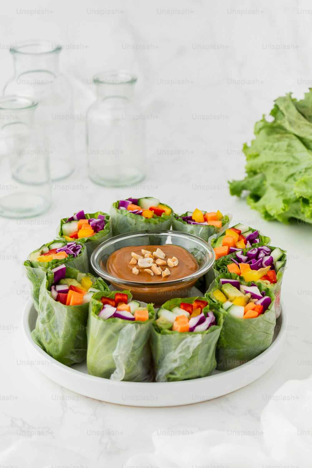 a plate of food with lettuce, carrots, and a dipping sauce