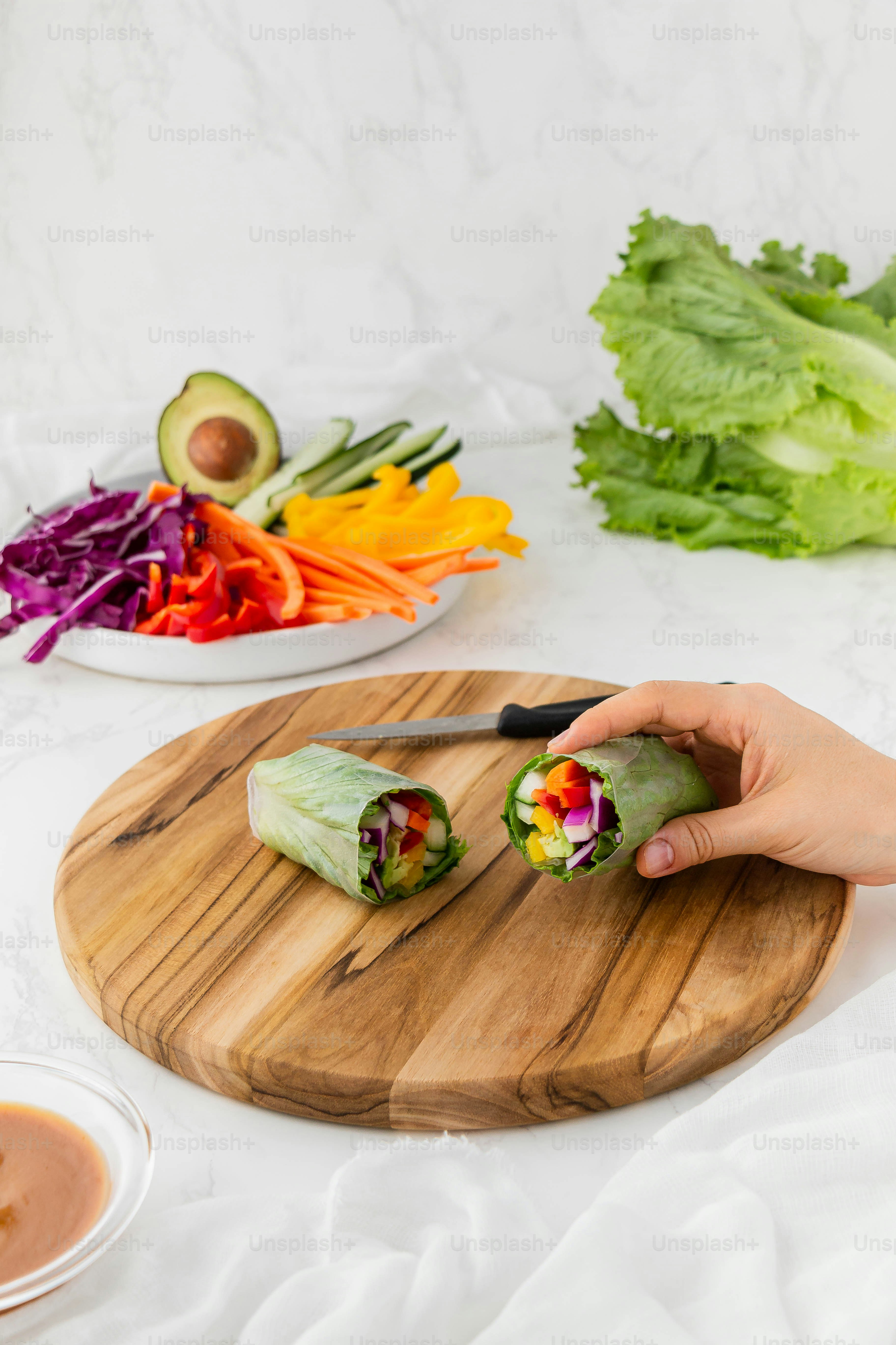a person cutting up a vegetable roll on a cutting board