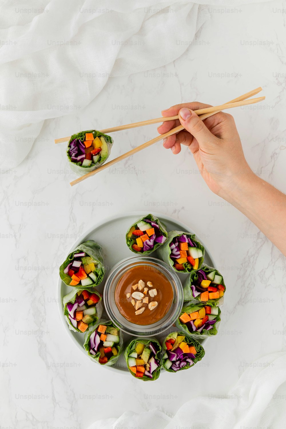 a person holding chopsticks over a plate of food