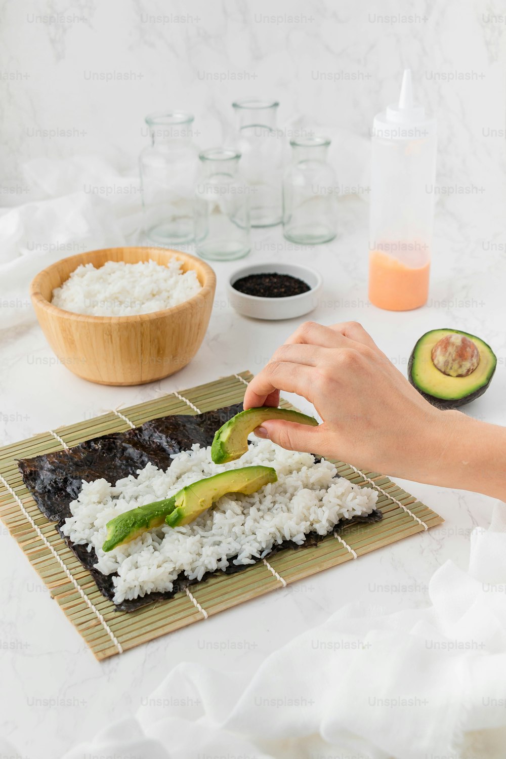 a person cutting a piece of sushi on a bamboo mat