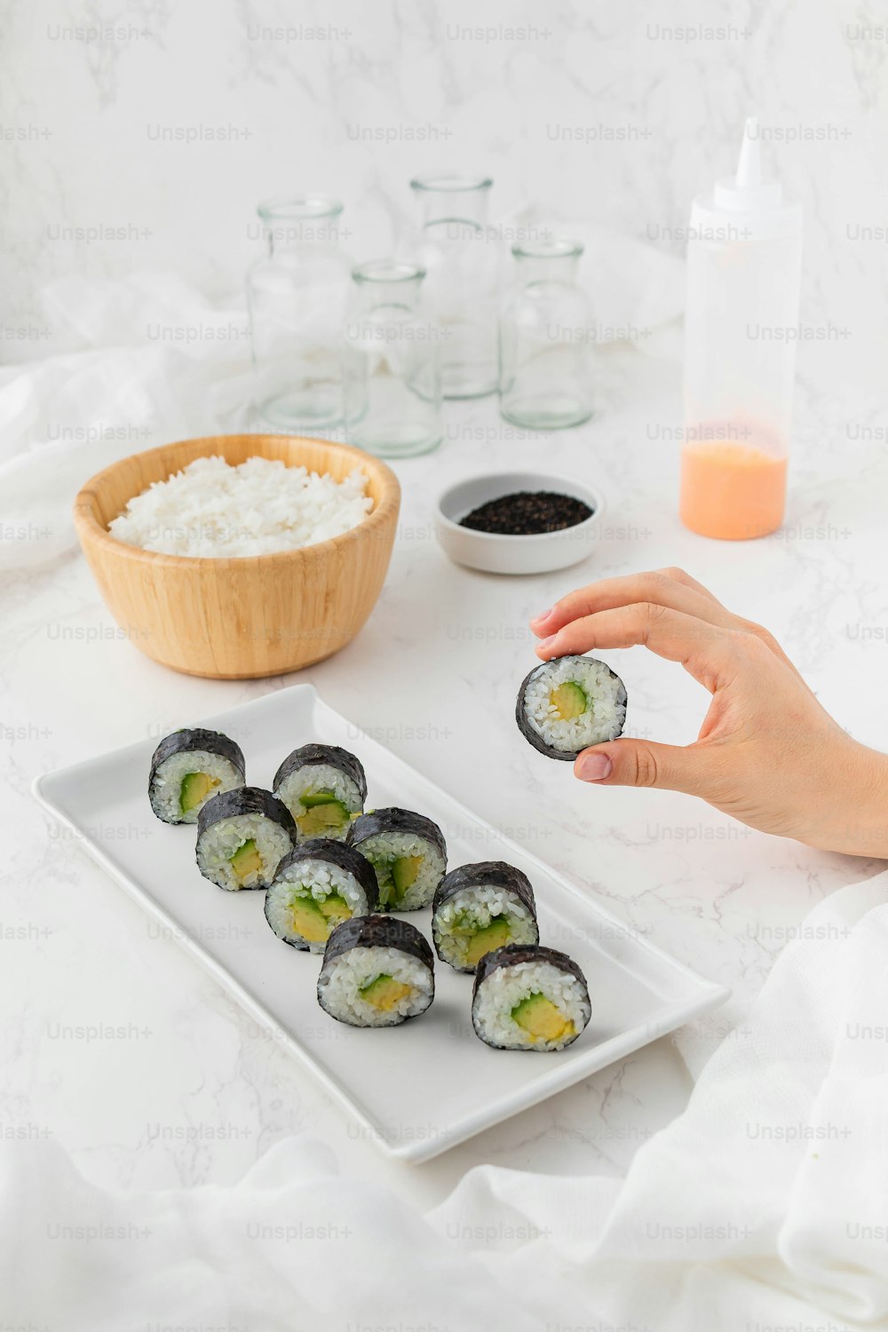 une personne tient un sushi à la main