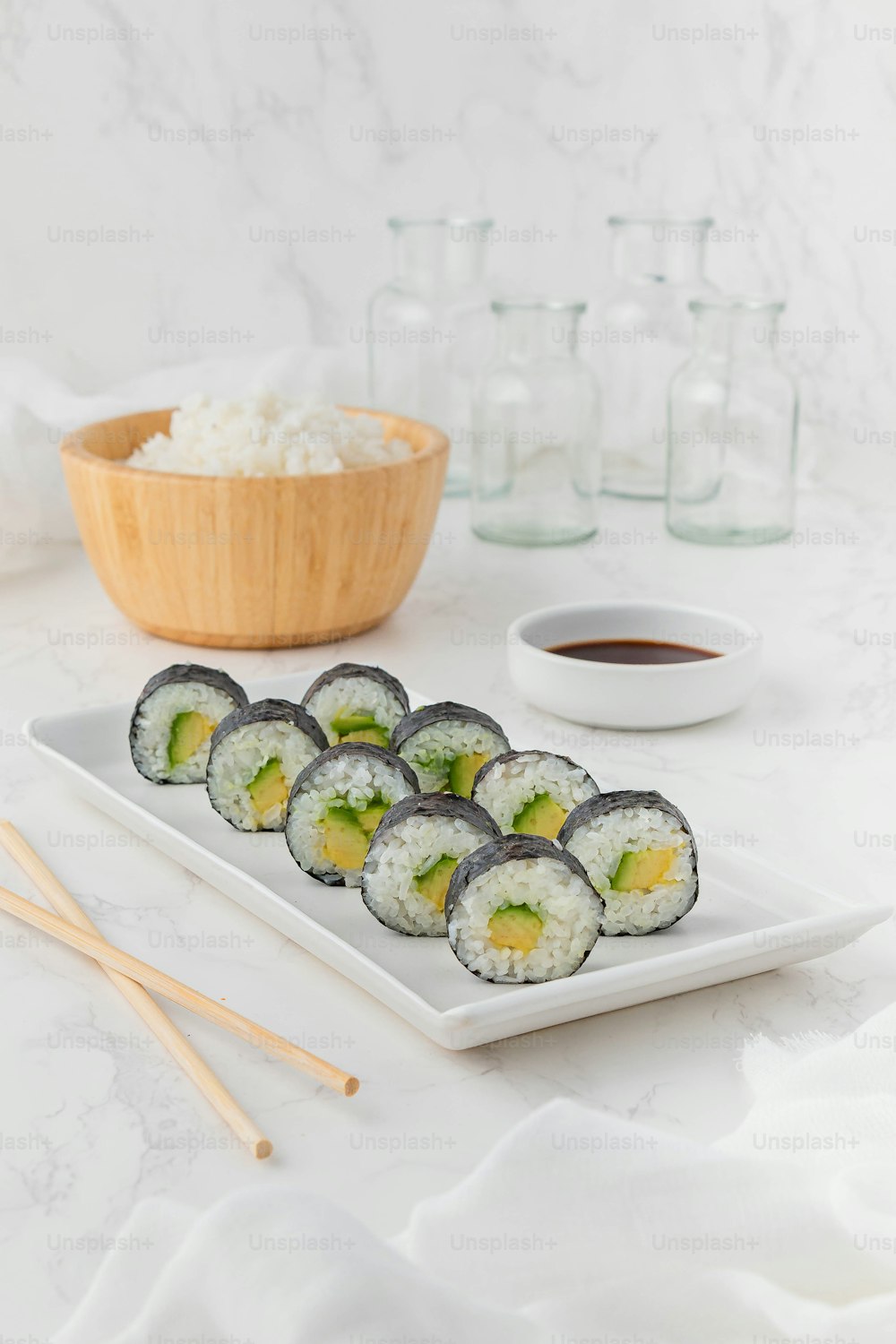 un plato blanco cubierto con sushi junto a un tazón de arroz