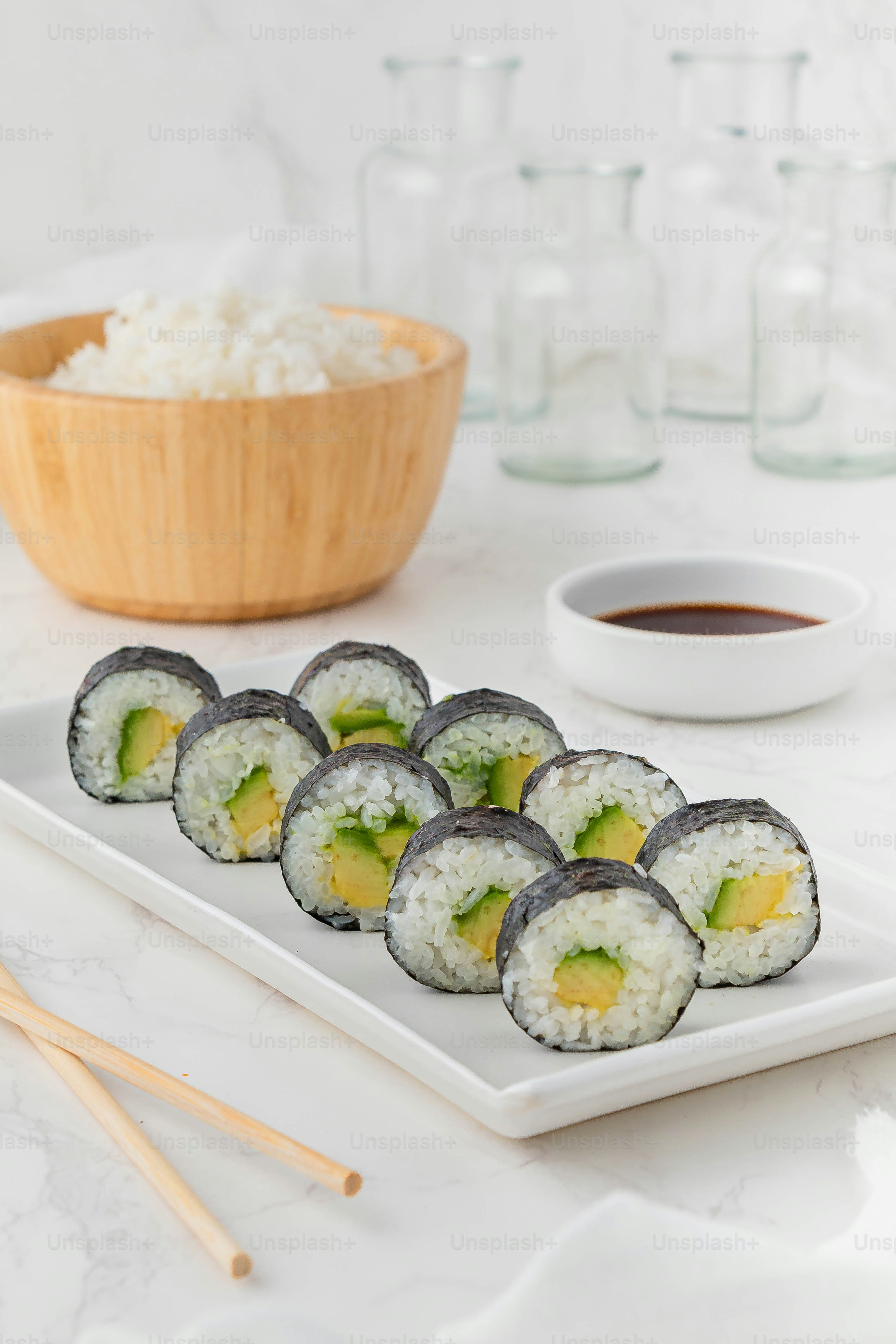 Un piatto bianco condito con sushi accanto a una ciotola di riso