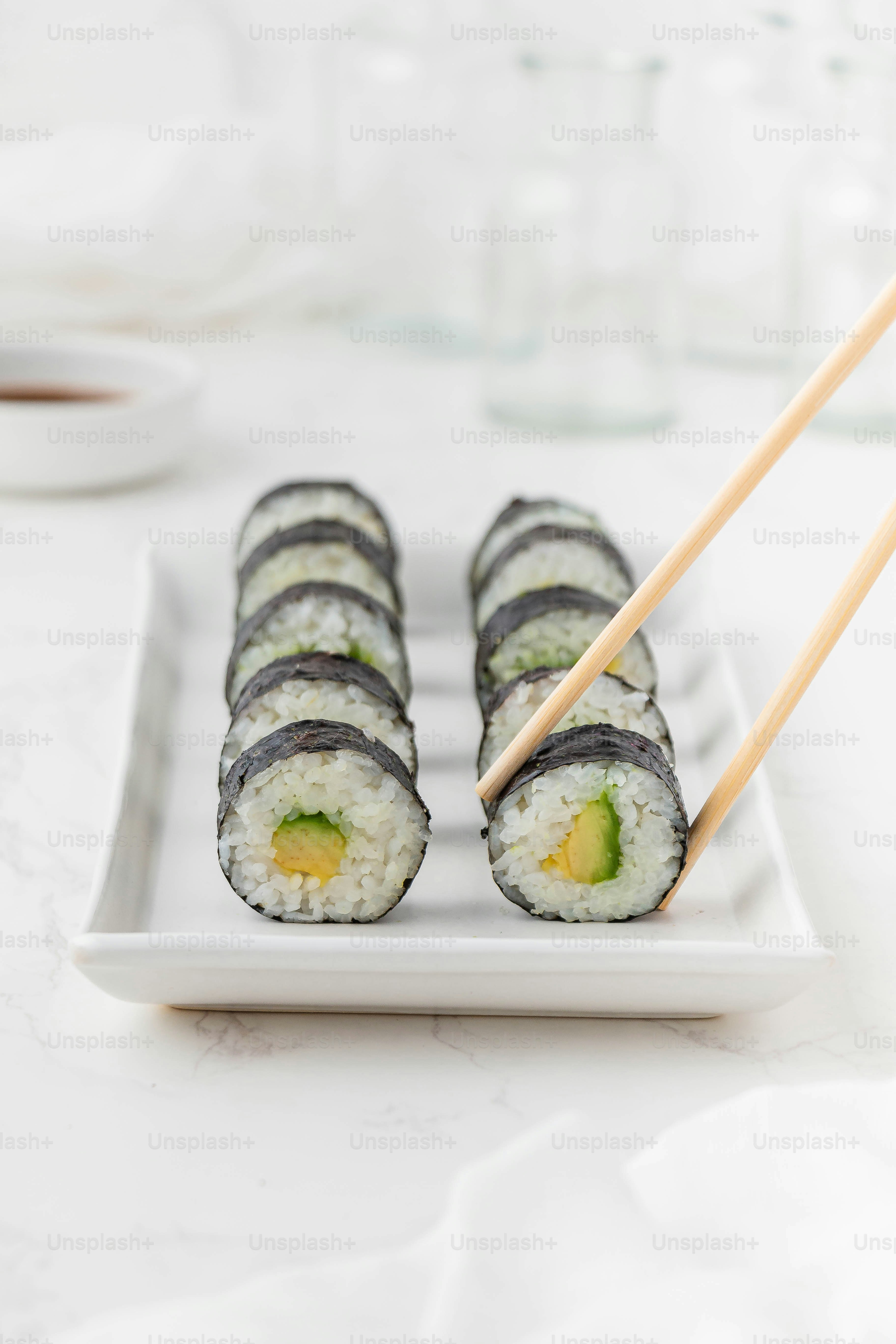 une assiette blanche garnie de sushis et de baguettes