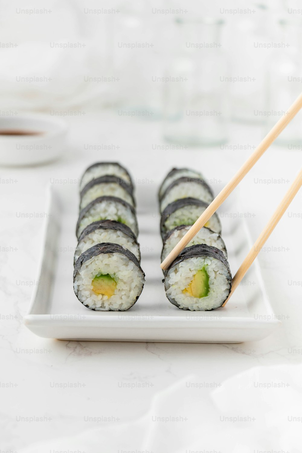 um prato branco coberto com sushi e pauzinhos