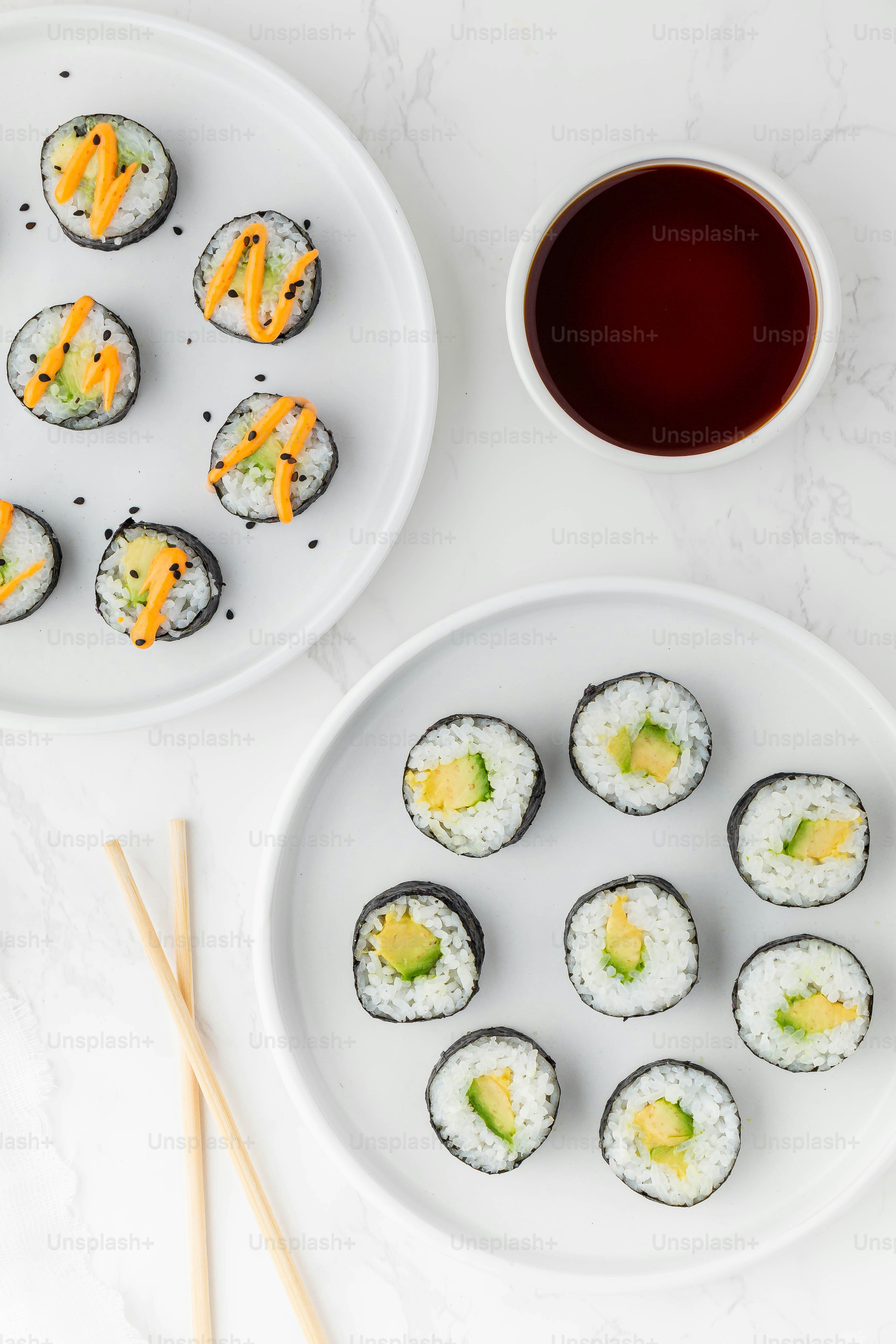 une assiette blanche garnie de sushis à côté d’une tasse de thé