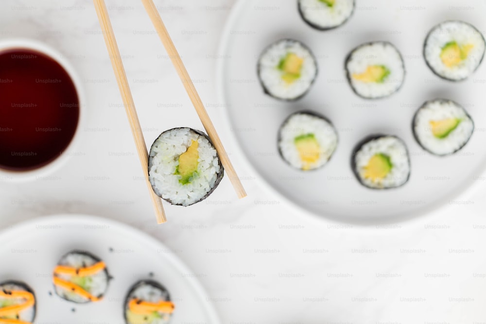 une assiette de sushis avec des baguettes à côté d’un bol de sauce