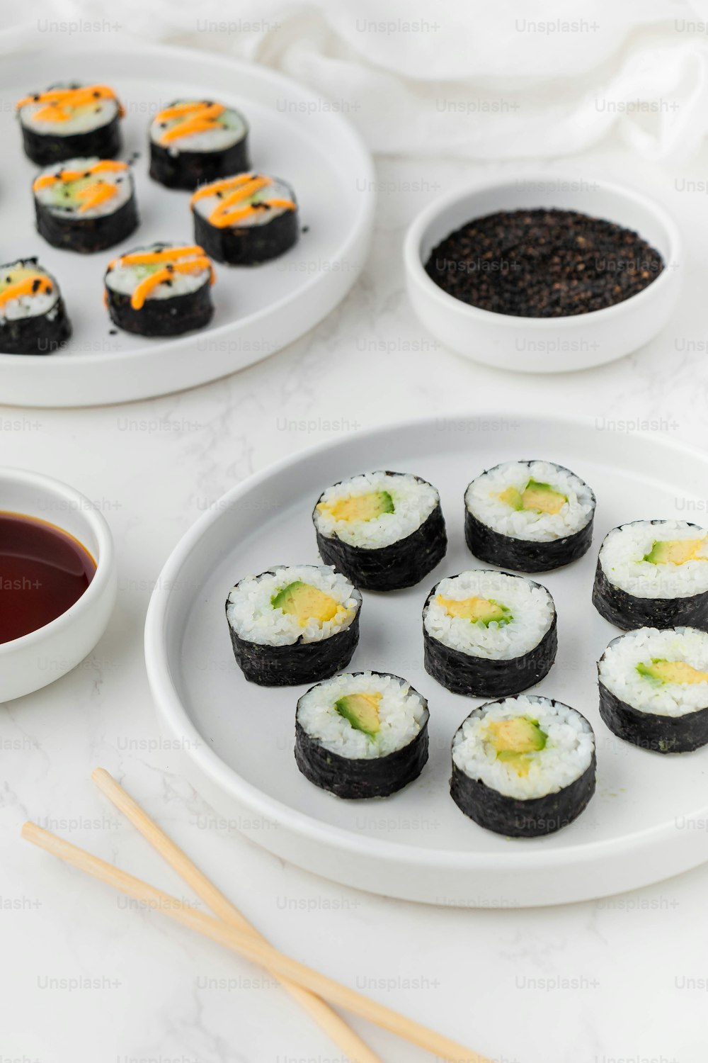 a plate of sushi next to a bowl of dipping sauce
