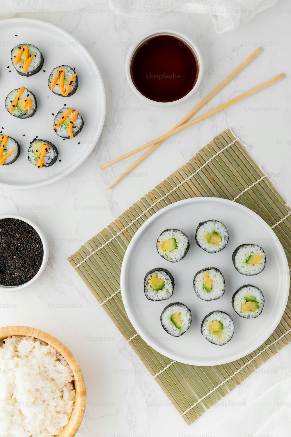 a plate of sushi next to a bowl of rice and a cup of tea